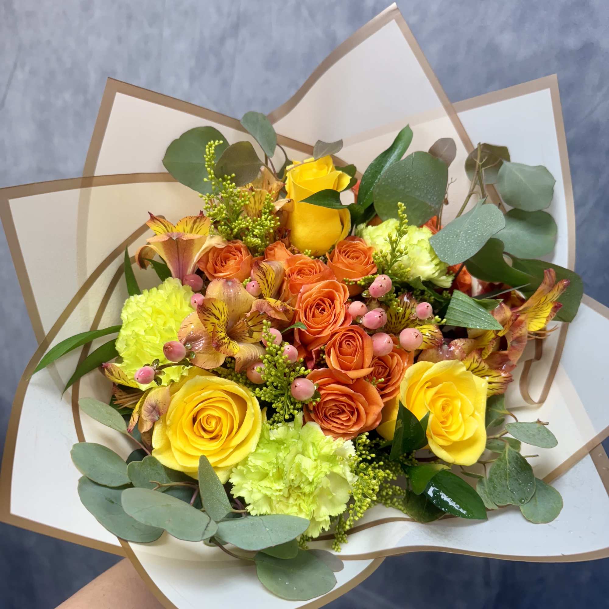 Bouquet of yellow and orange roses with green and pink accents