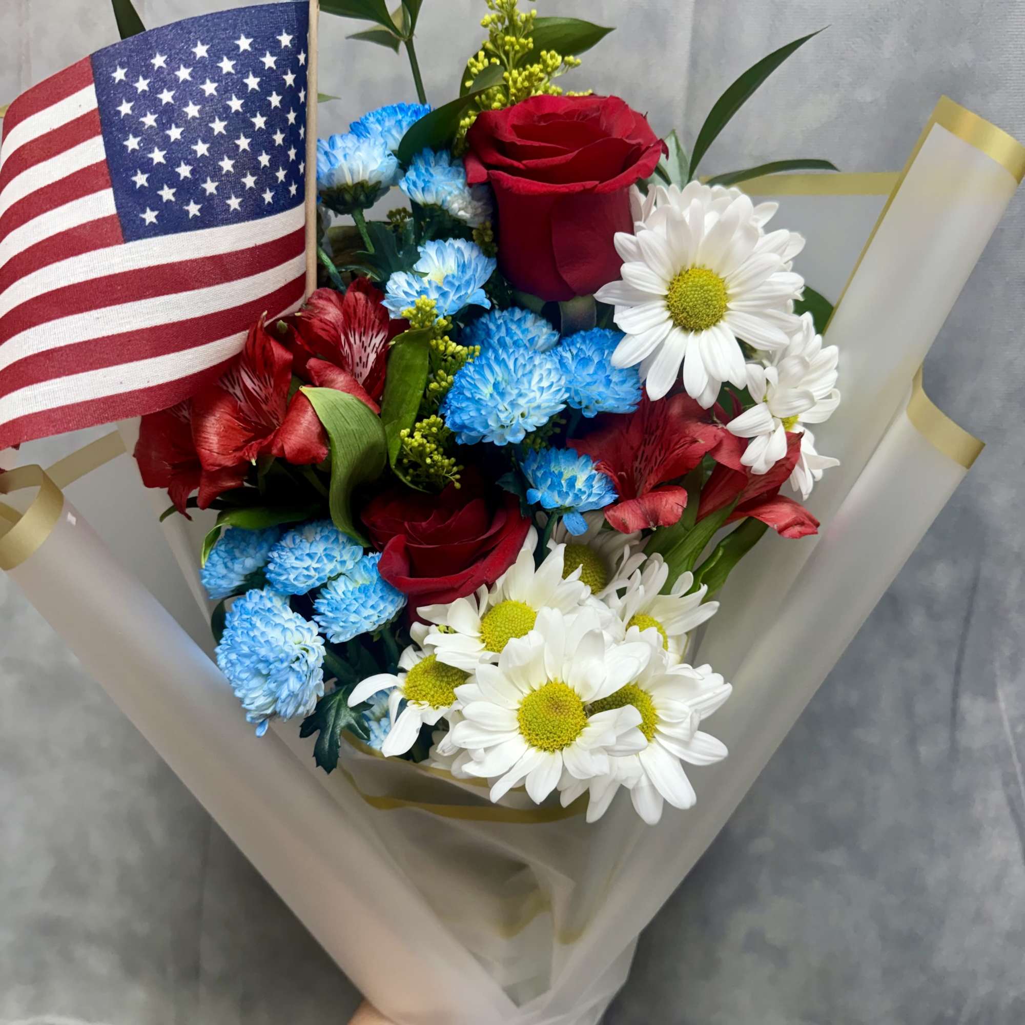 Bouquet of red roses, blue and white daisies, and an American flag