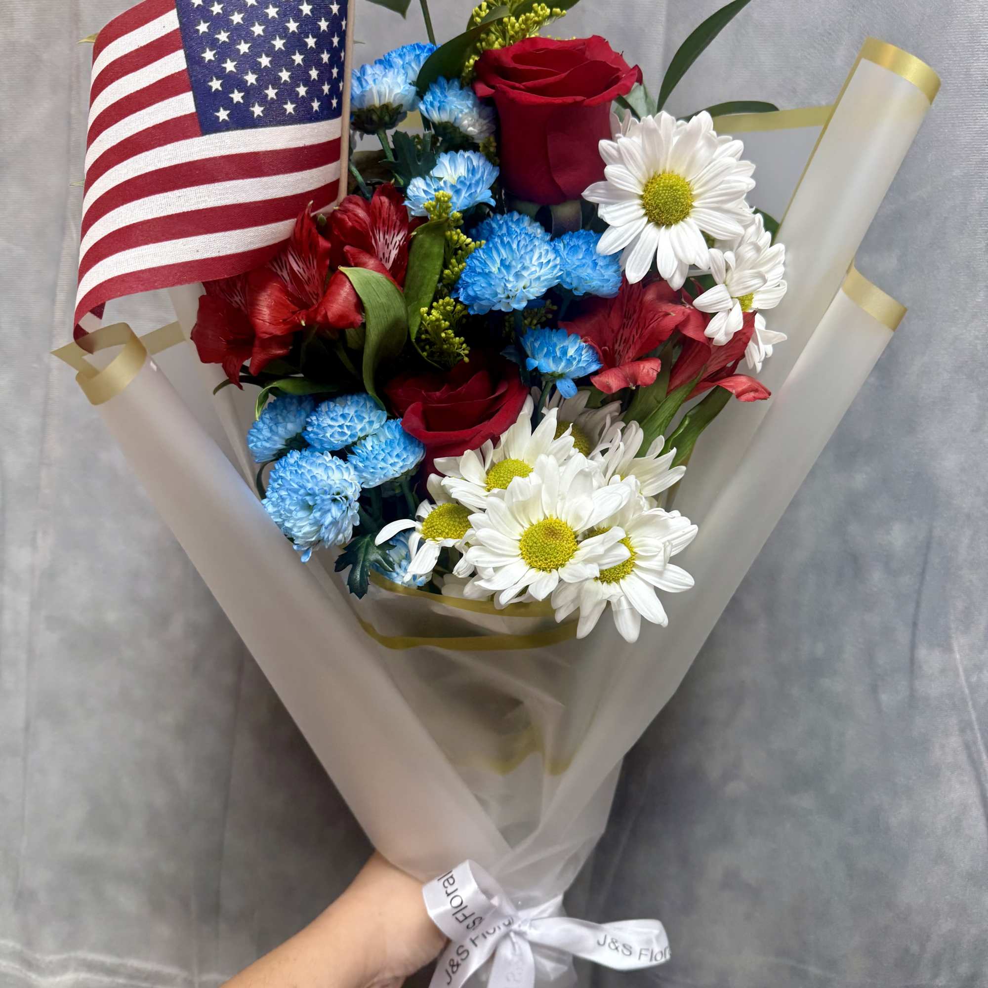 Bouquet of red roses, blue mums, and white daisies with an American flag