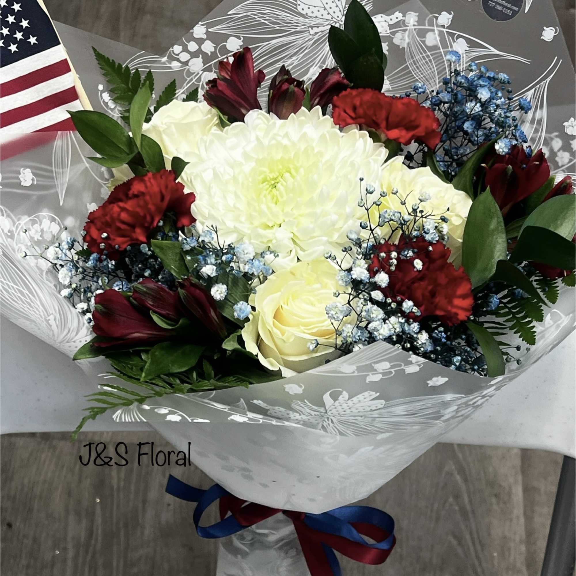 Bouquet of white roses, red carnations, and dark red flowers in clear wrap
