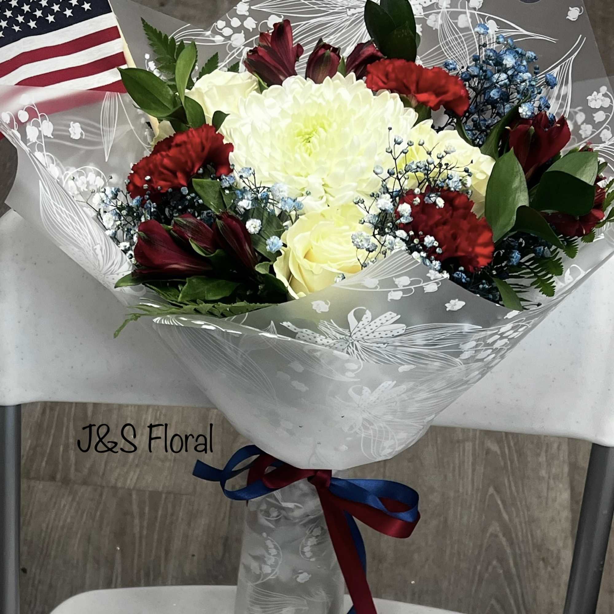 Bouquet of red, white, and blue flowers wrapped in clear paper with an American flag