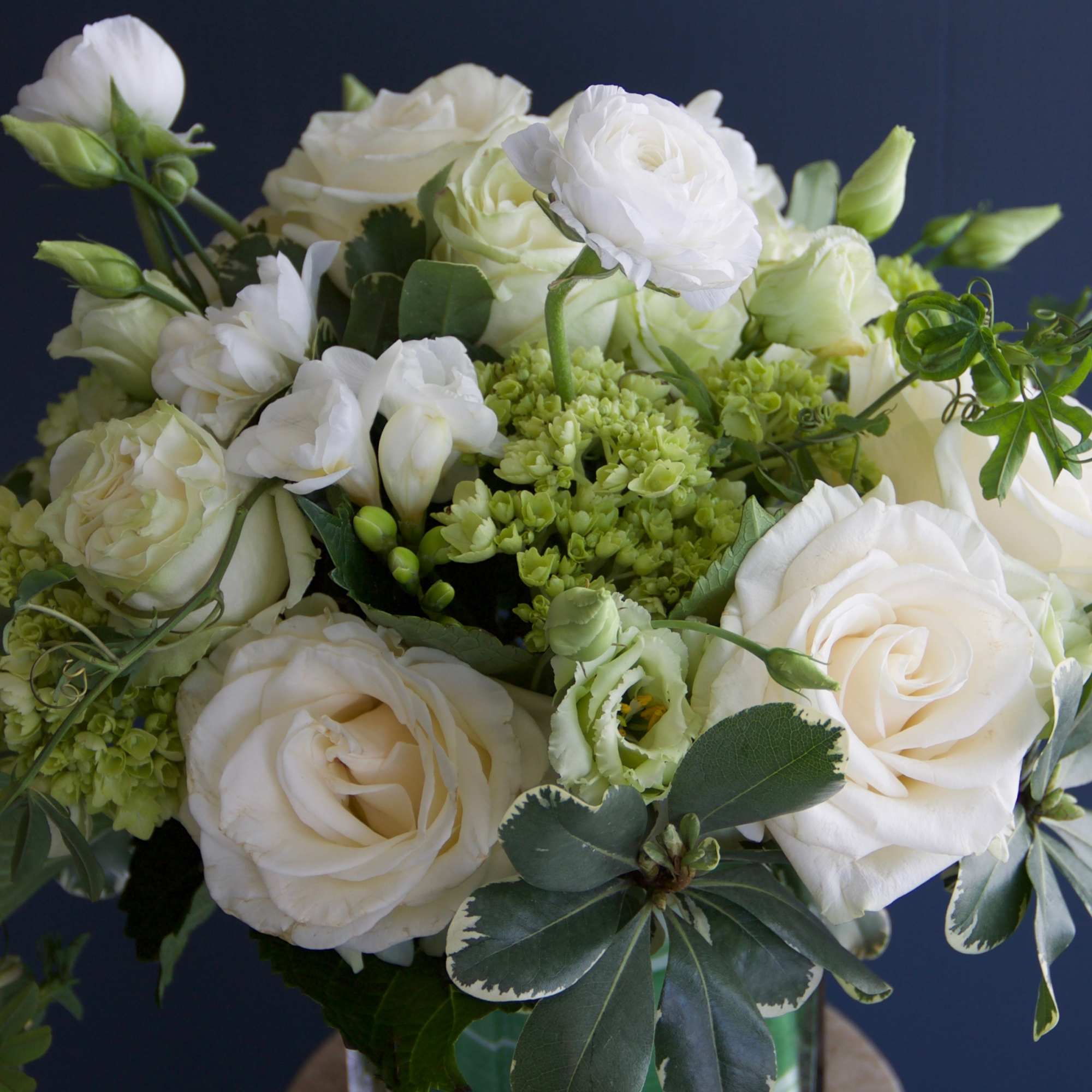 White rose bouquet with green accents against a dark background