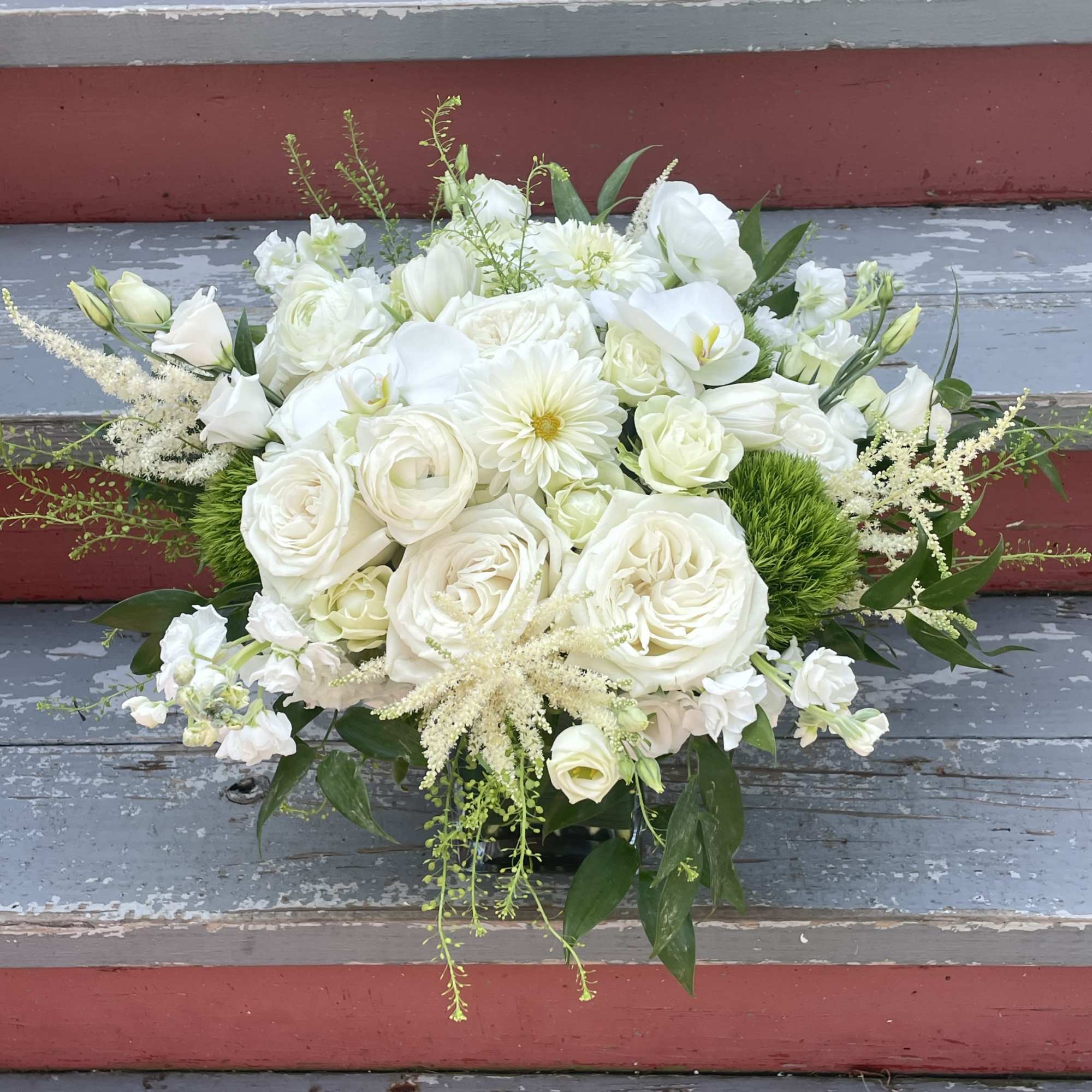White floral arrangement with roses, calla lilies, and daisies