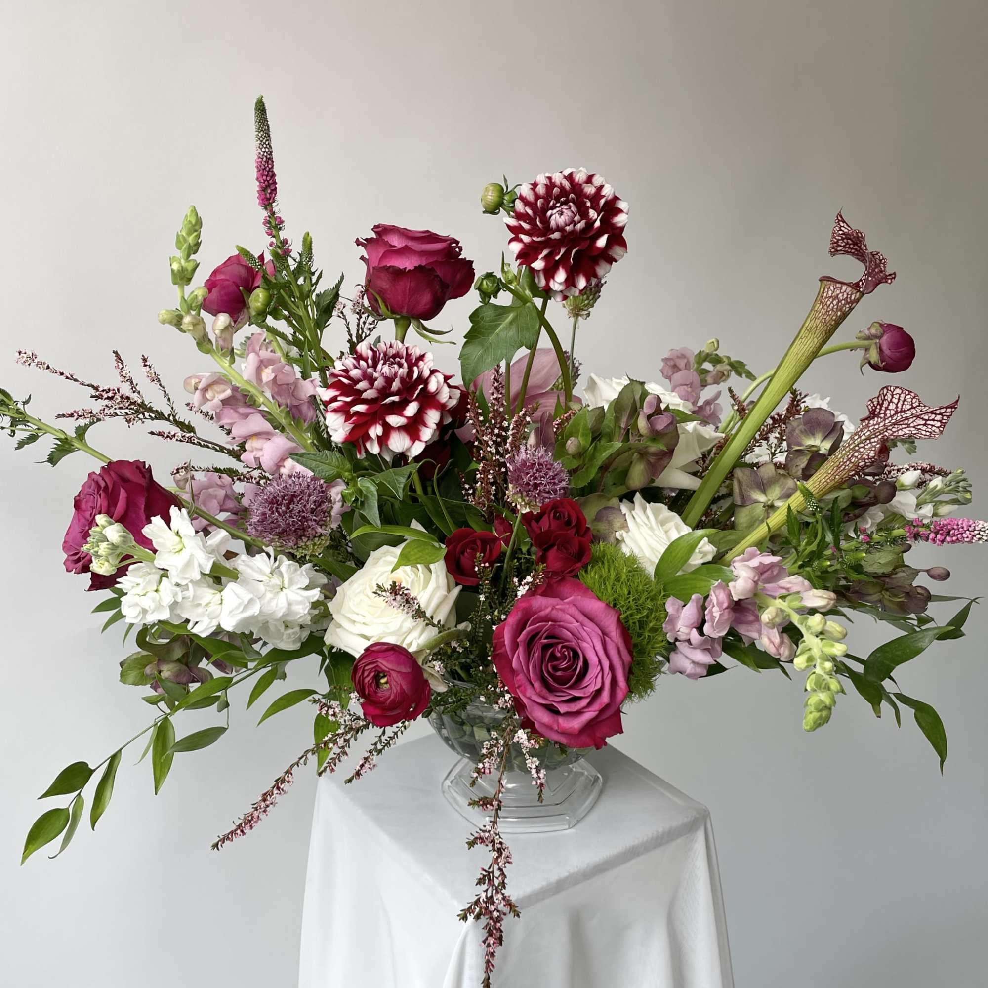 Large mixed bouquet in a clear glass vase with pink, white, and burgundy flowers