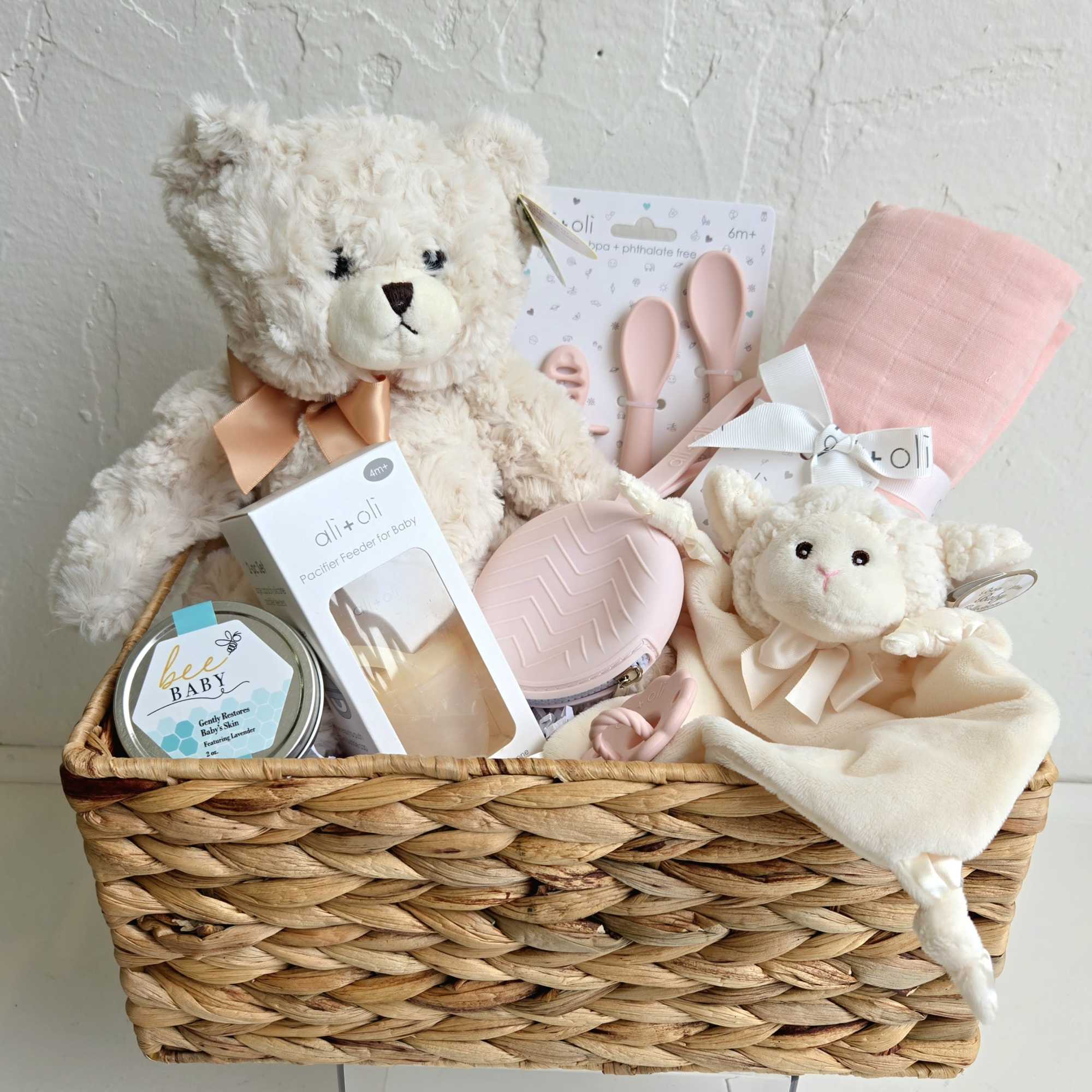 Baby gift basket with teddy bears, pacifier items, and pink accessories