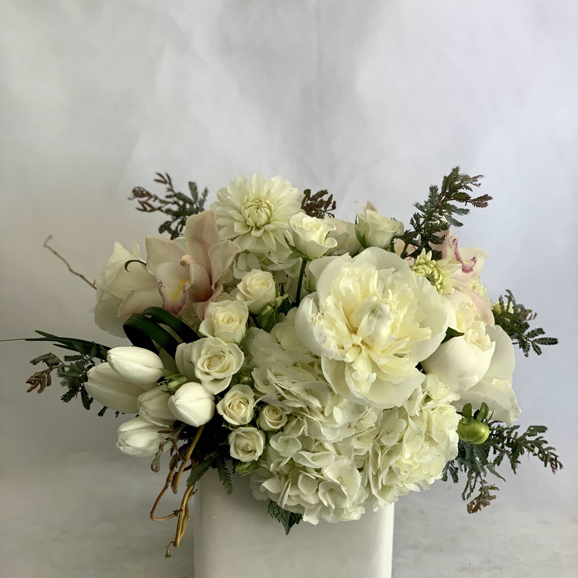 White floral arrangement in a square ceramic vase