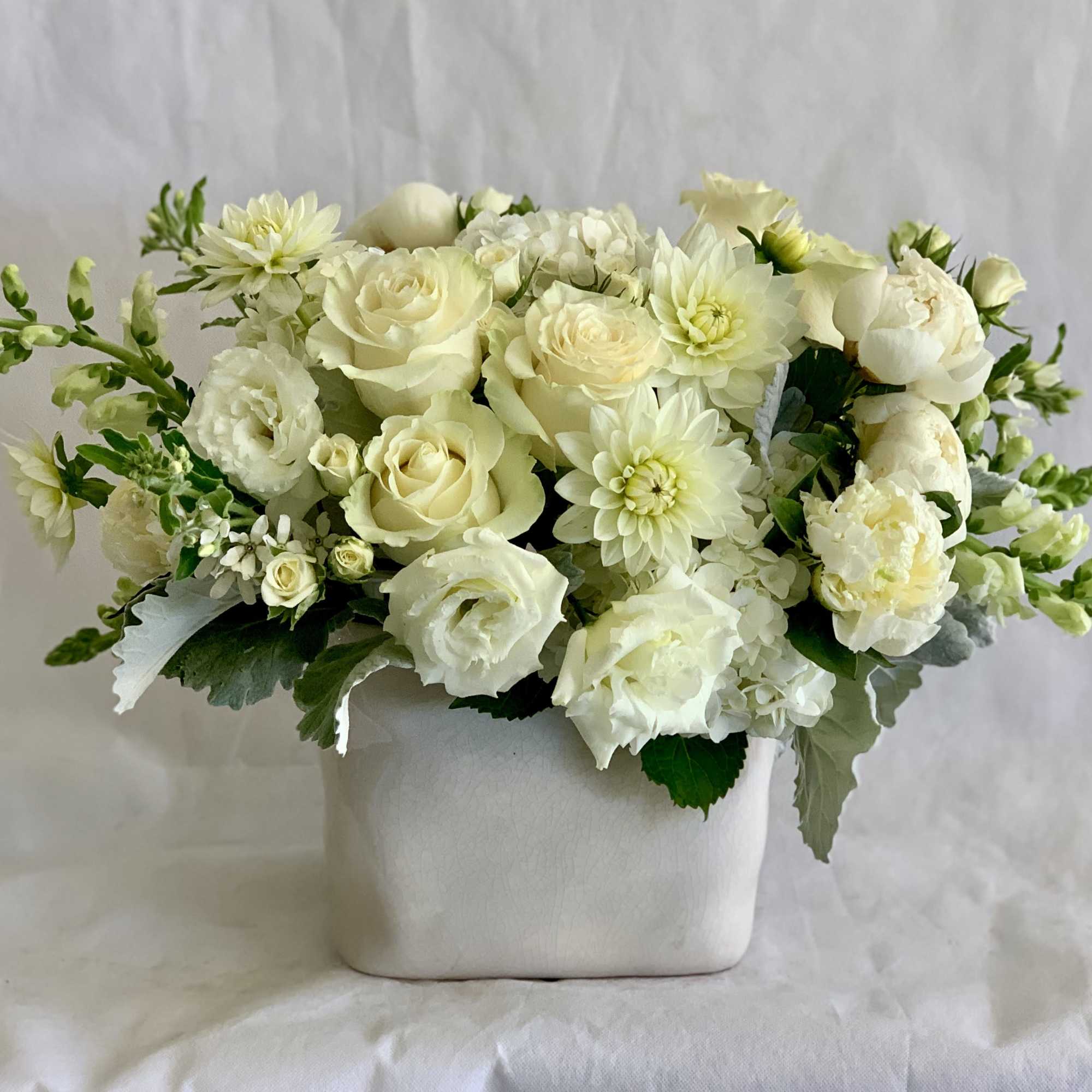 White floral arrangement in a square ceramic vase