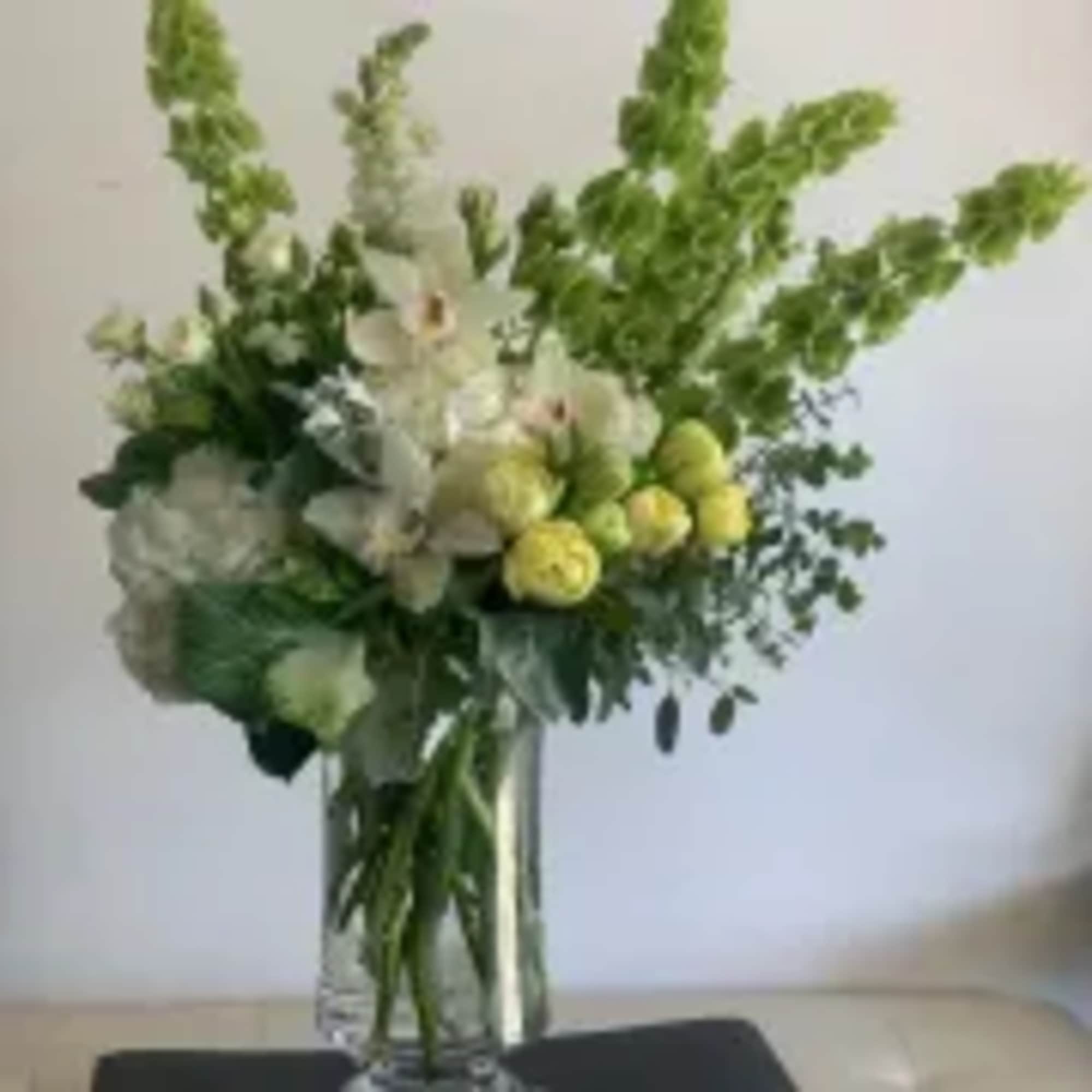 White and yellow floral arrangement in a clear glass vase