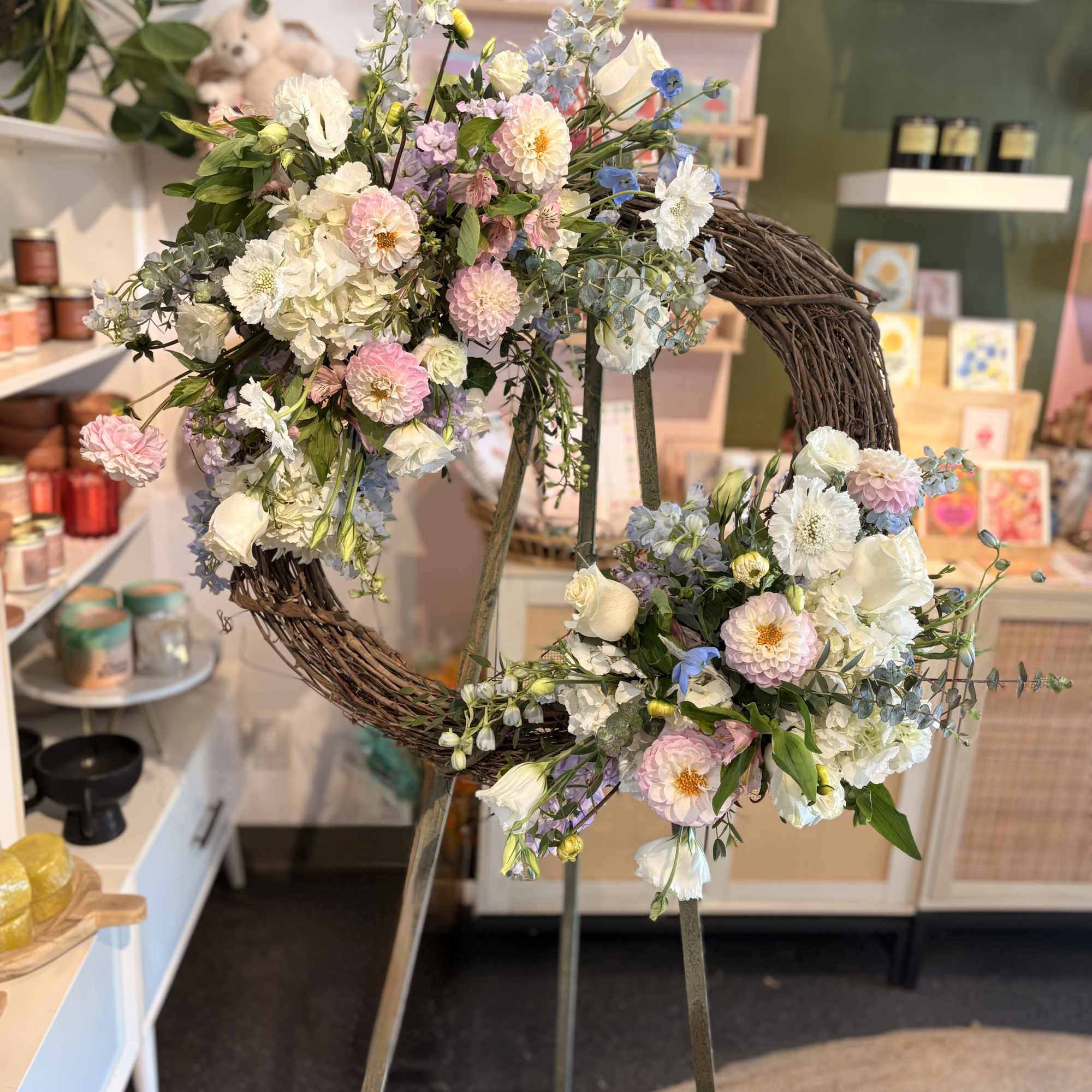 Two floral wreaths on a stand with pastel flowers and white blooms