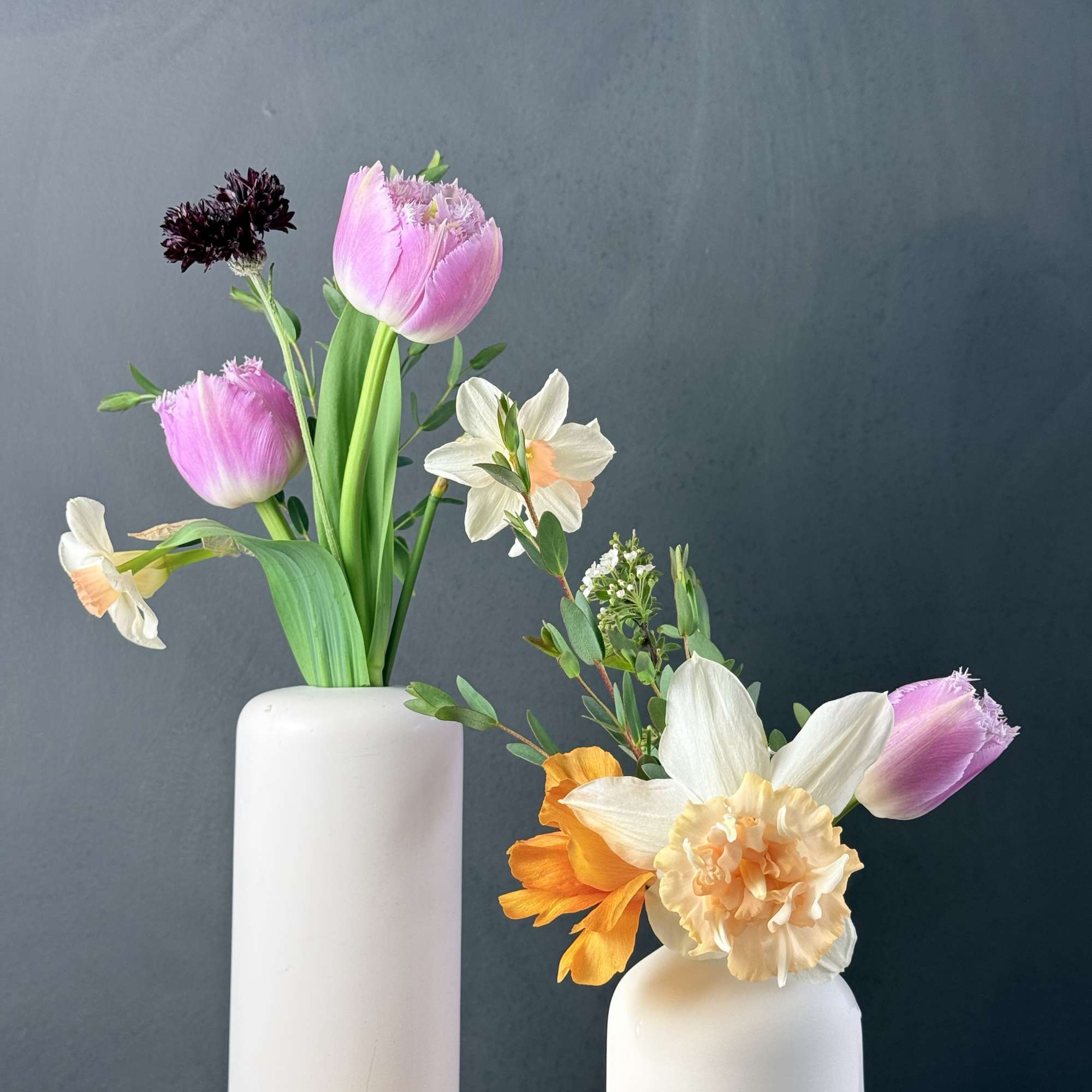 Two small floral arrangements in white vases with pink and white blooms