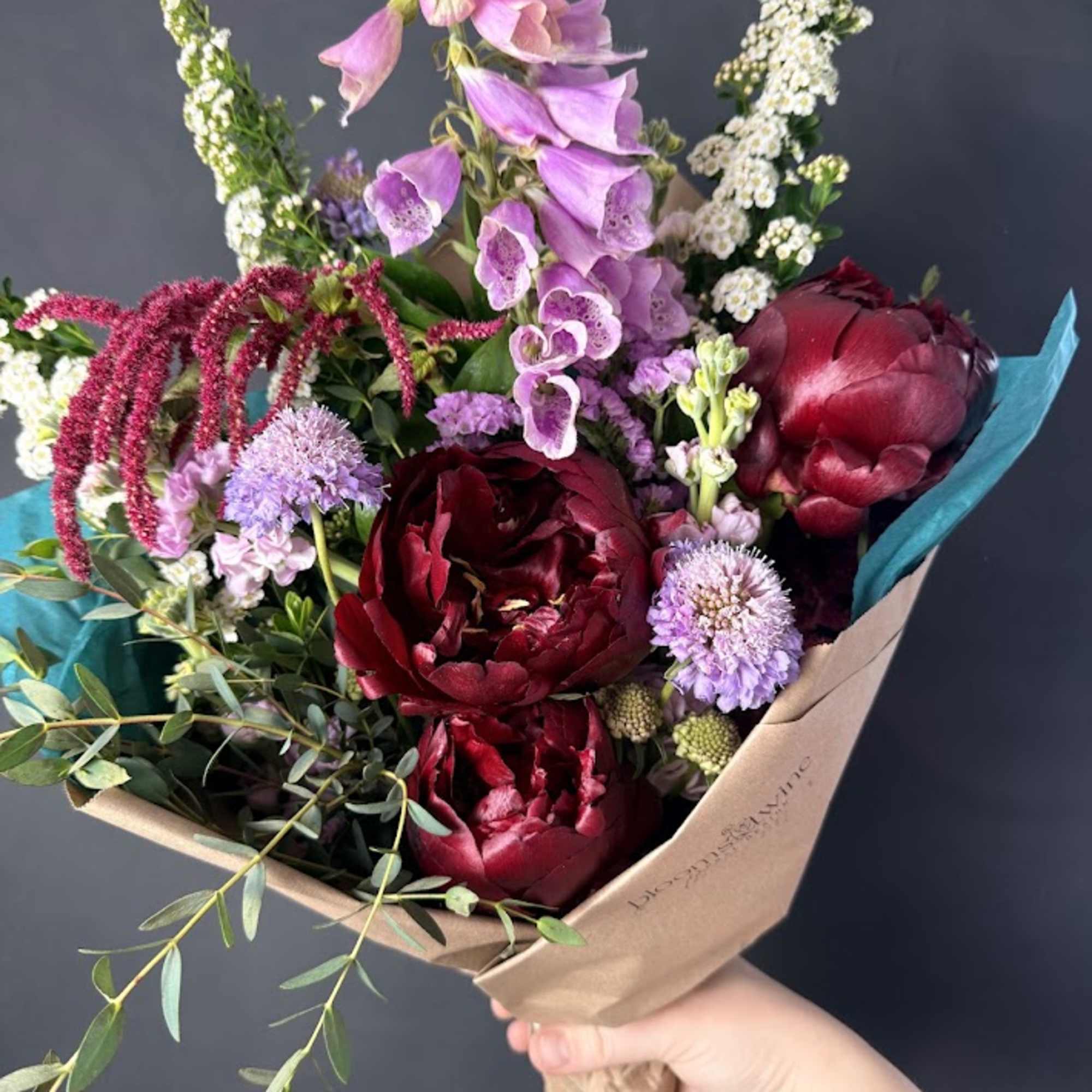 Bouquet of burgundy and pink flowers wrapped in brown paper