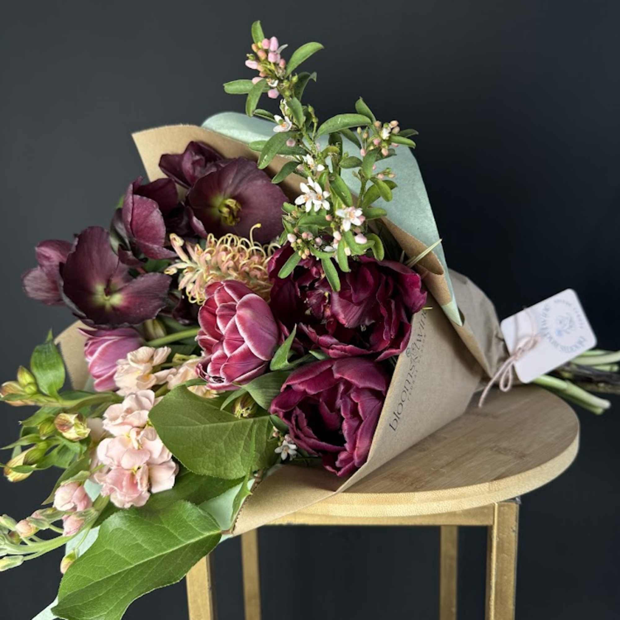 Bouquet of deep burgundy and pink flowers wrapped in kraft paper