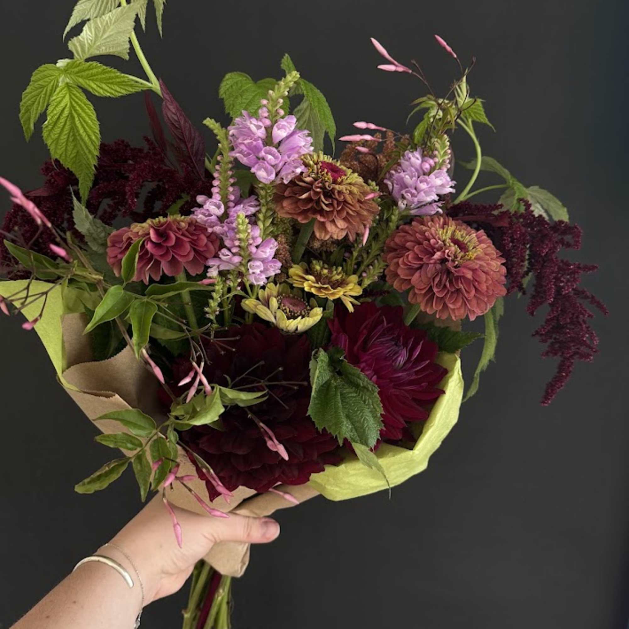 Handheld bouquet of burgundy, pink, and lavender flowers