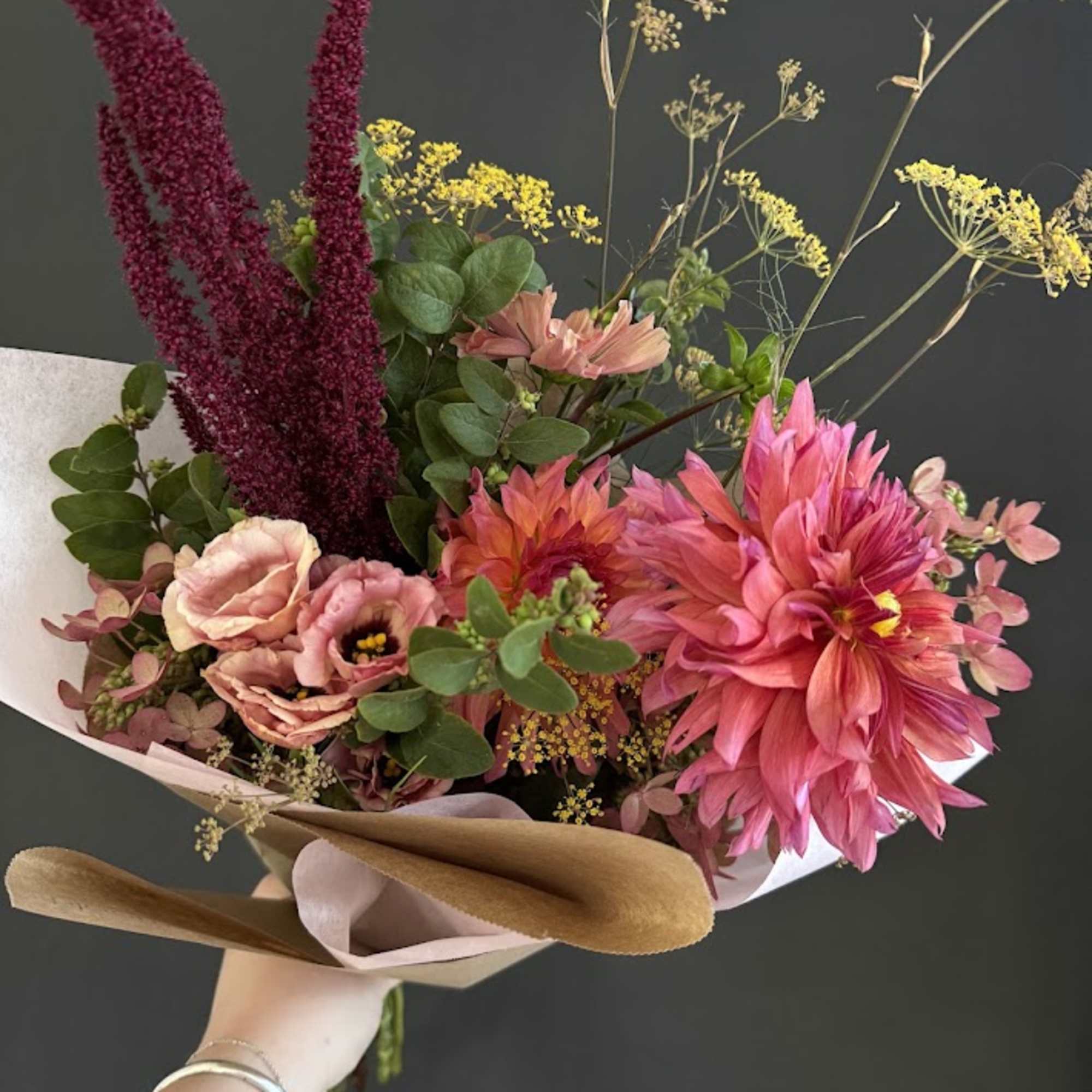 Hand-tied bouquet of pink and magenta flowers with tan wrapping