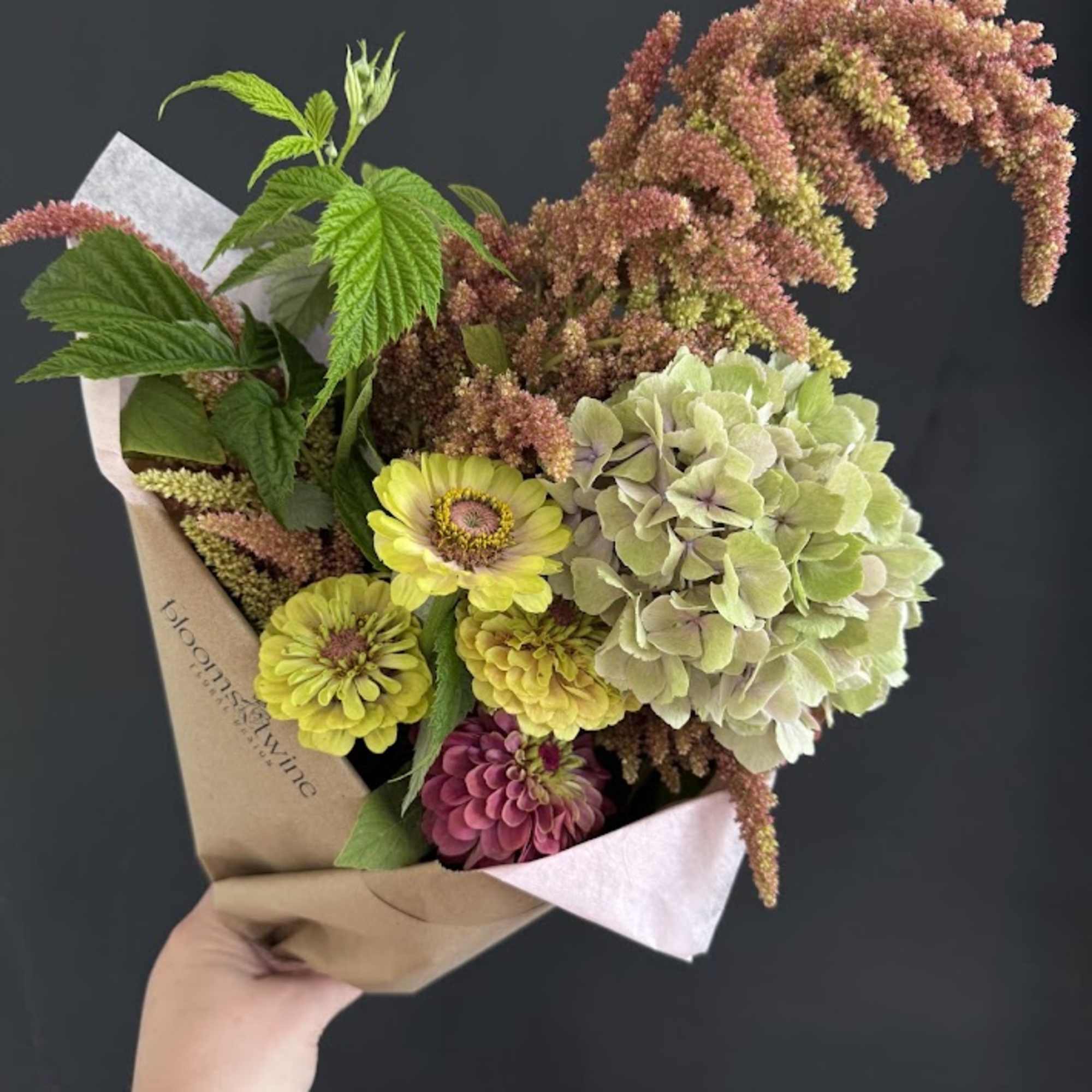 Handheld bouquet with yellow and pink flowers and pale green hydrangea