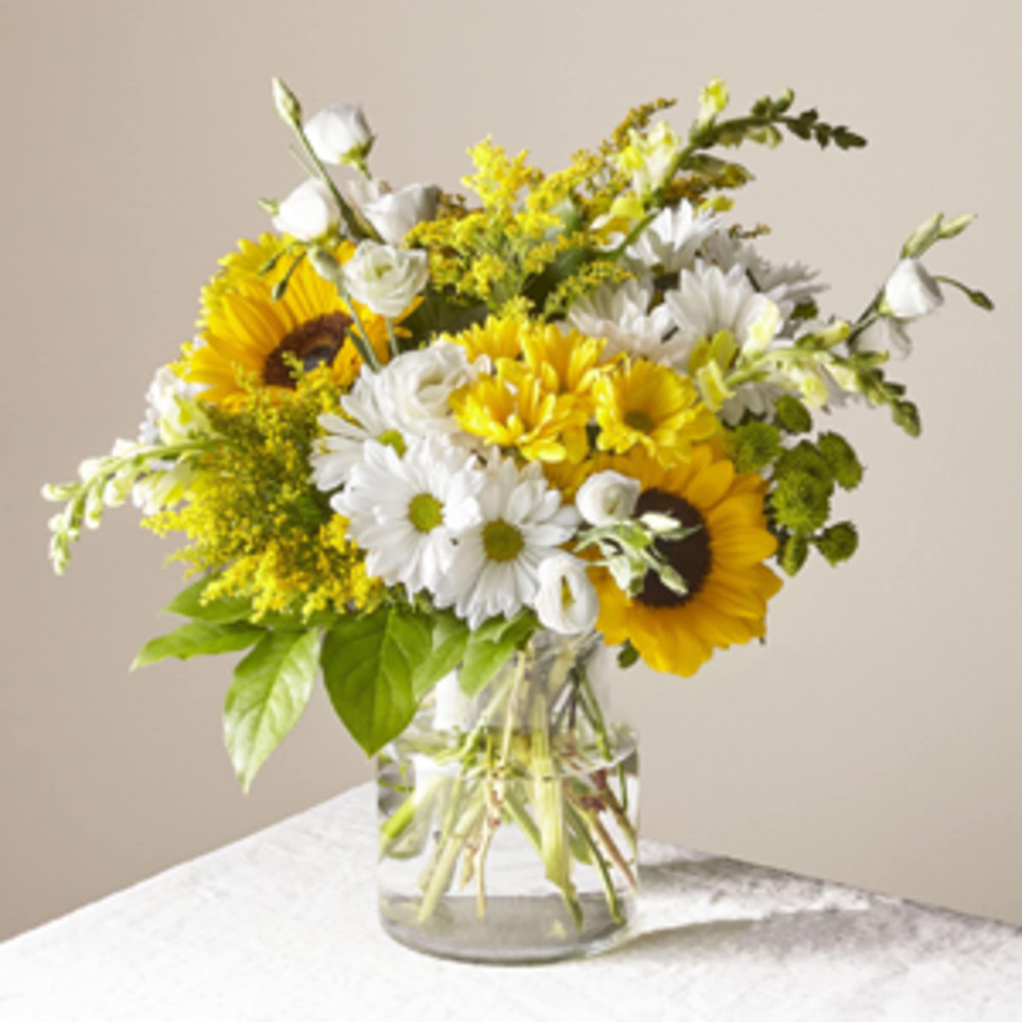 Bouquet of sunflowers and white daisies in a clear glass vase