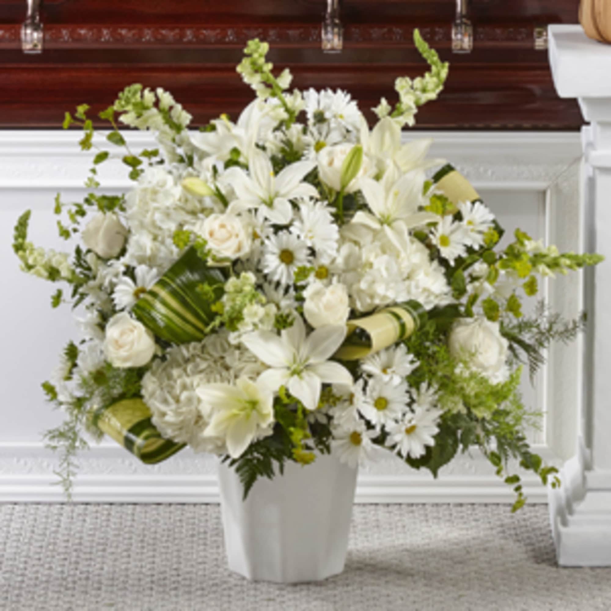 White lilies and daisies arranged in a white vase