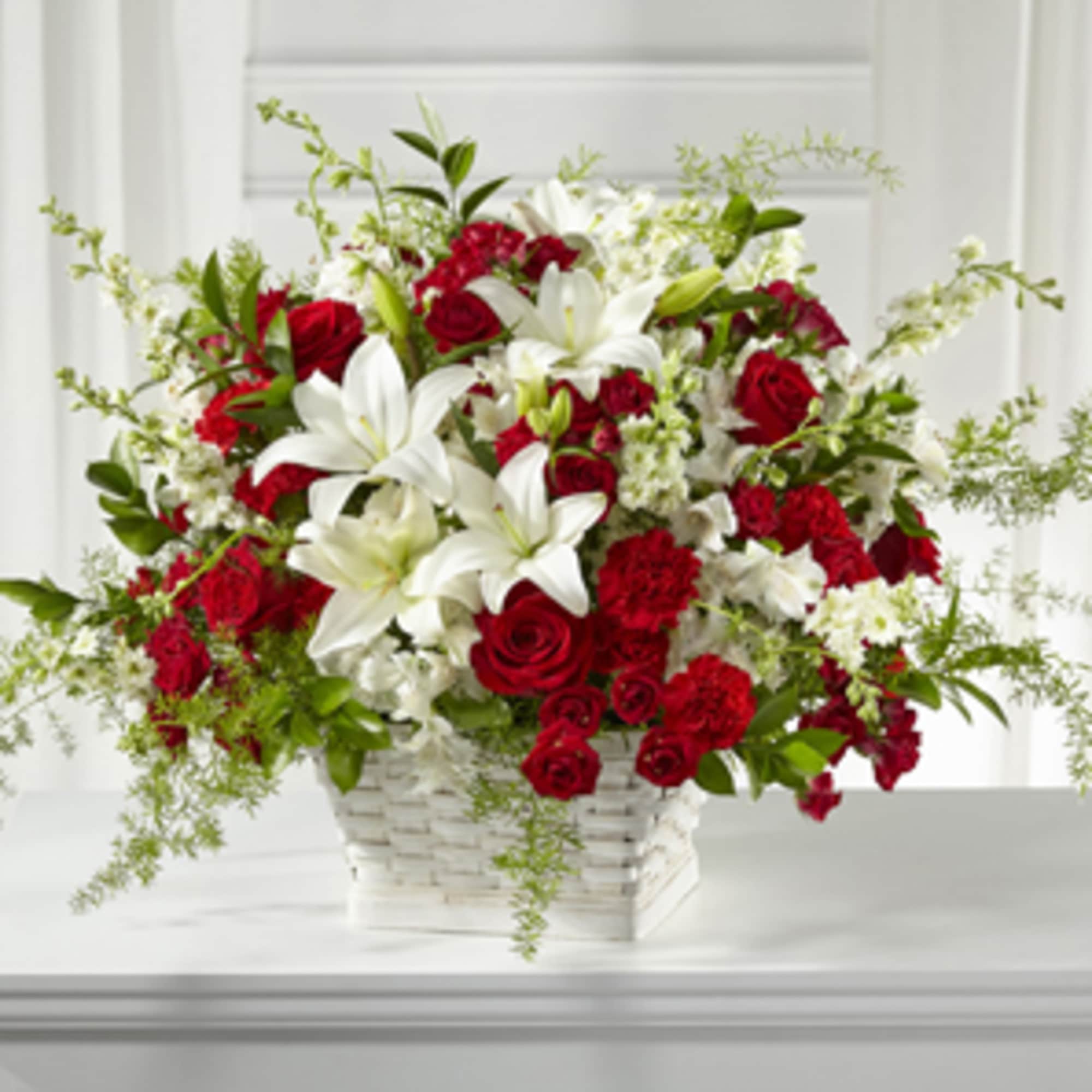 Red roses and white lilies arranged in a white basket