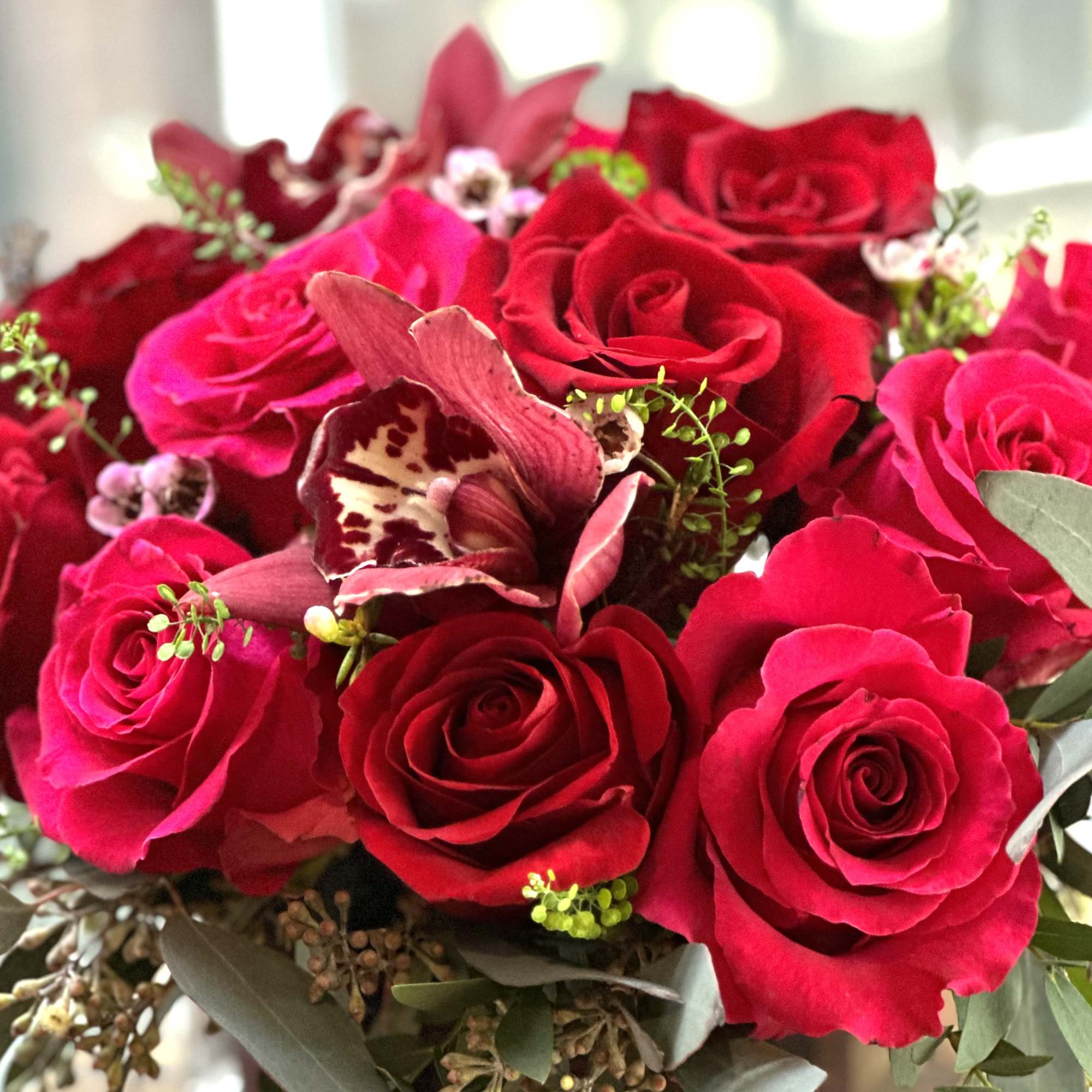 Bouquet of red roses with a pink orchid accent