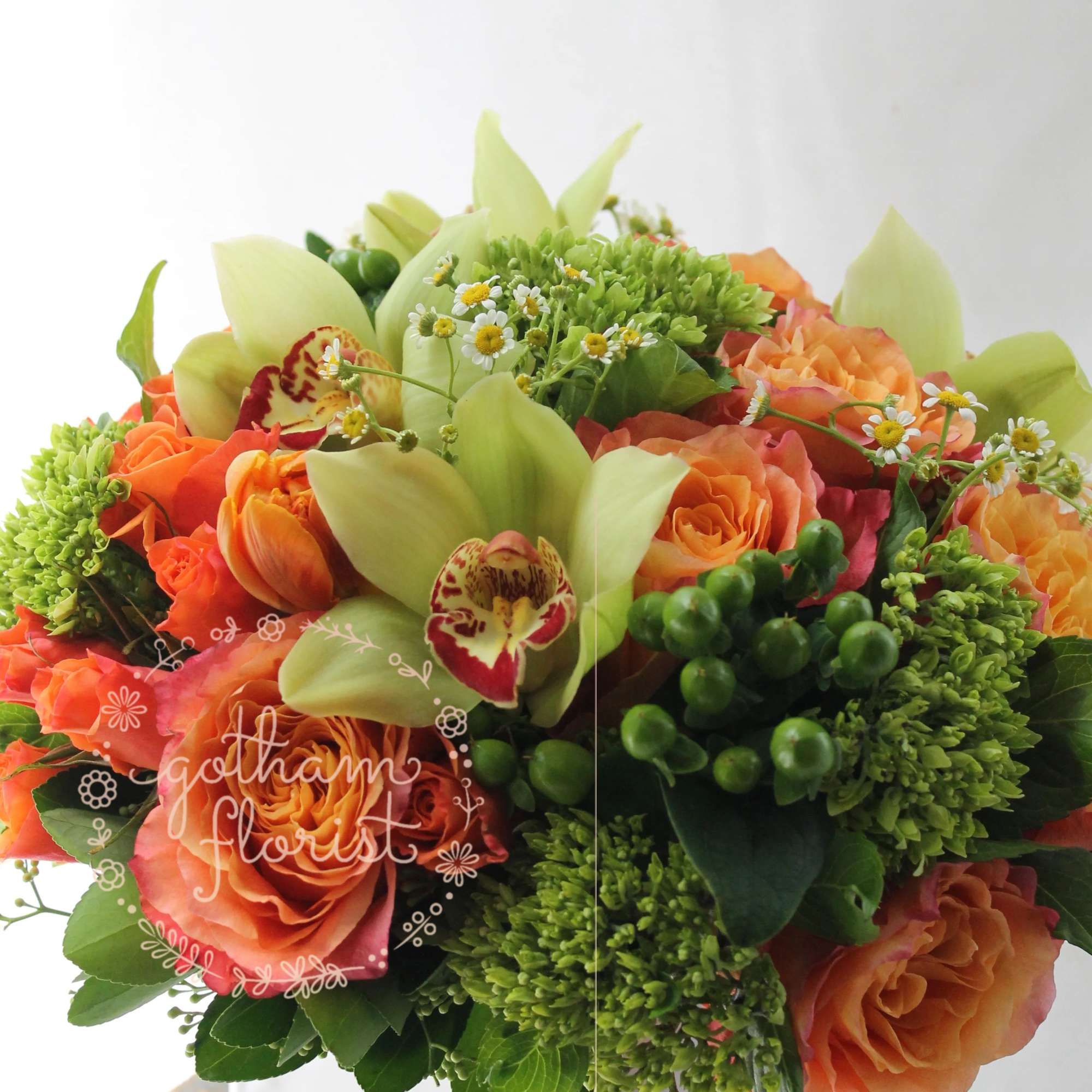 Orange roses and green orchids in a white square vase