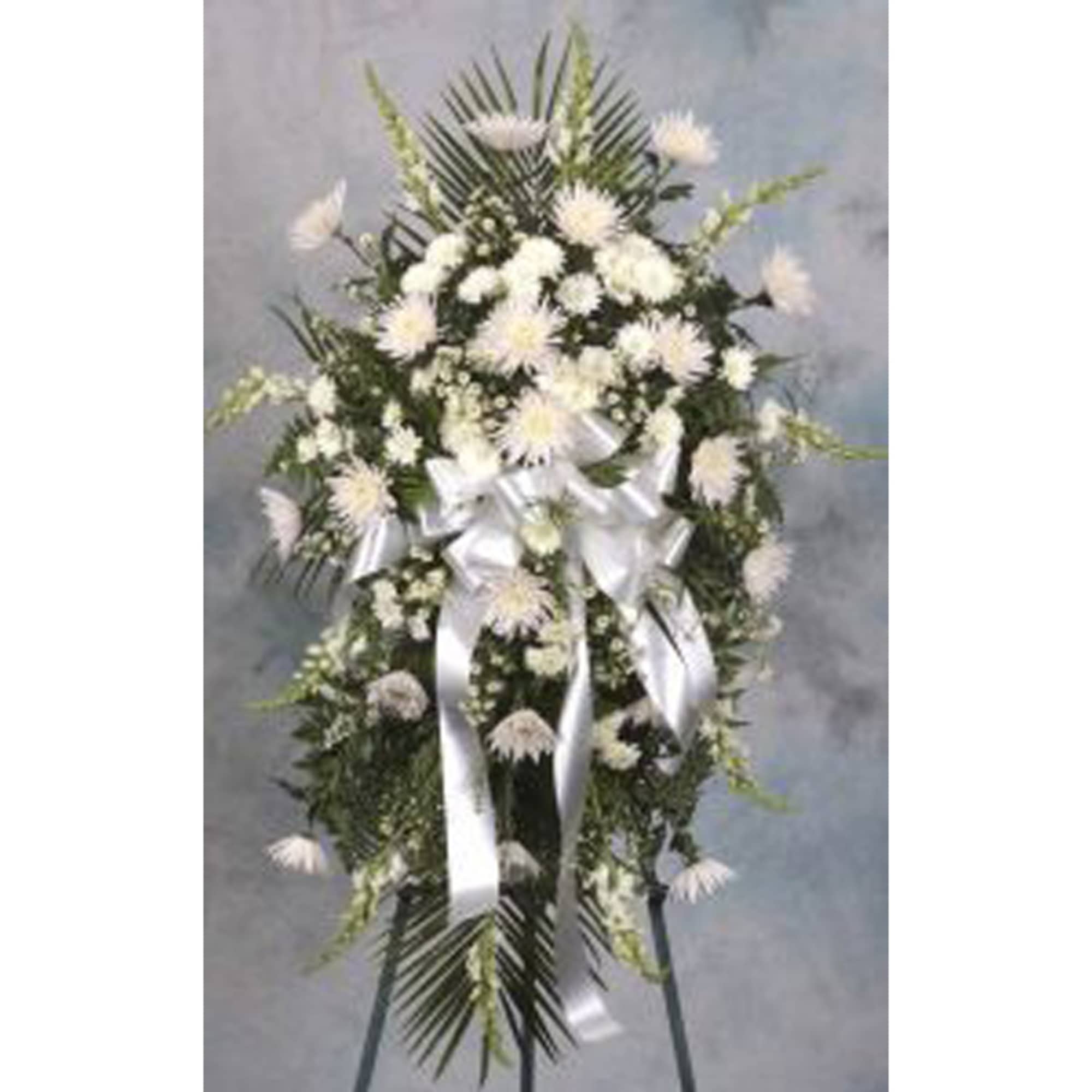 Tall white standing spray with mums and carnations on an easel, accented with a large white ribbon bow