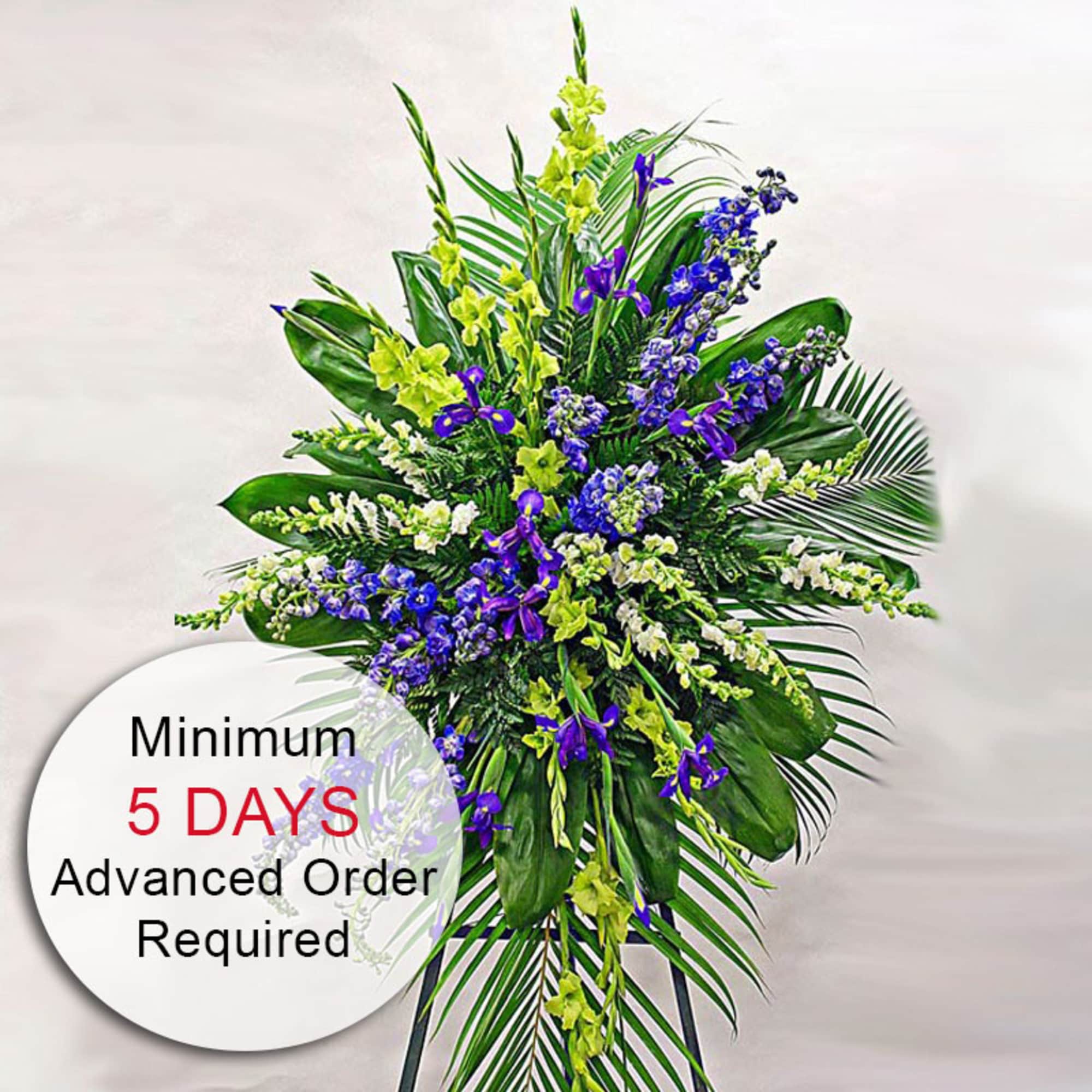 Tall standing spray of purple, white, and green flowers on an easel