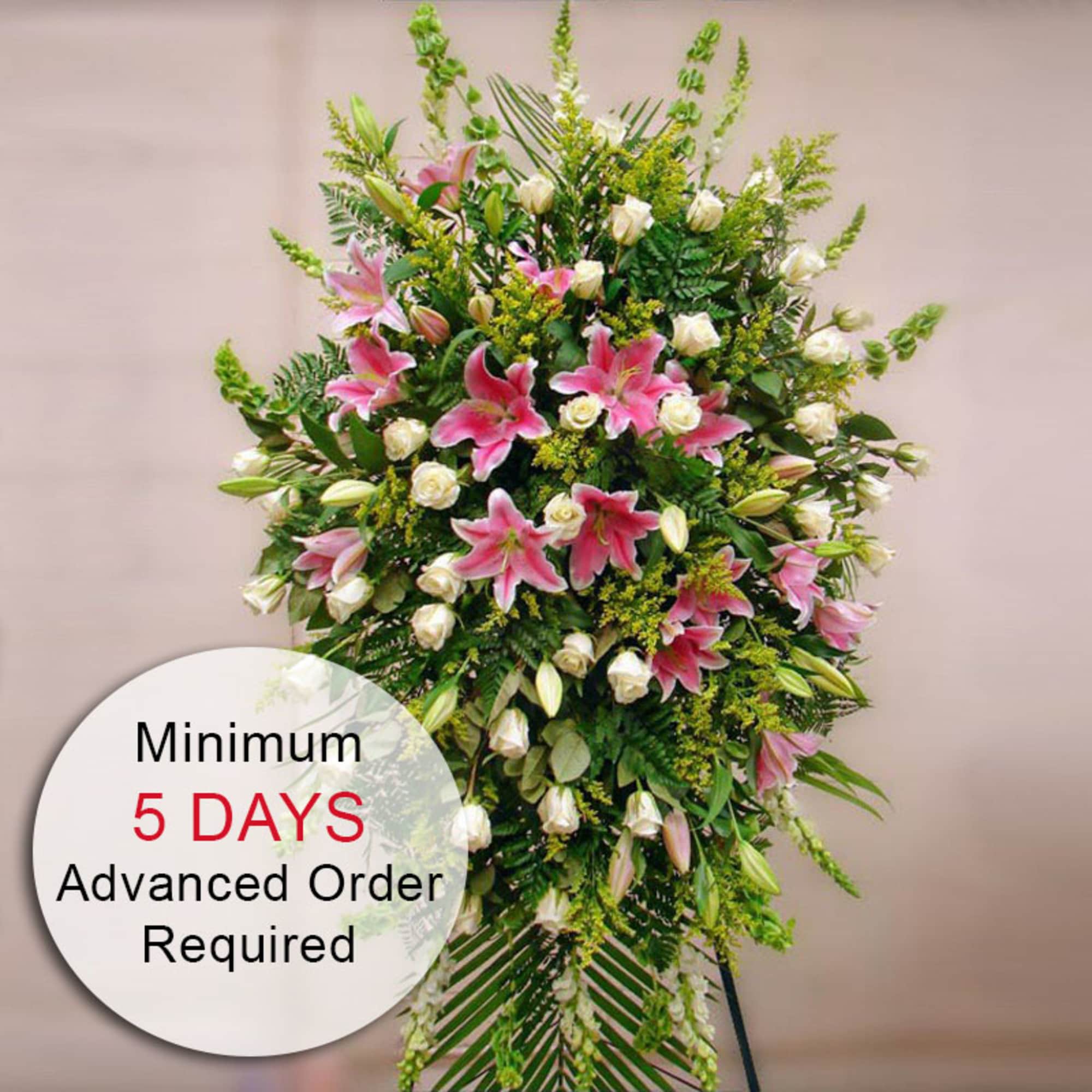 Tall standing spray with pink lilies and white roses on a green backdrop