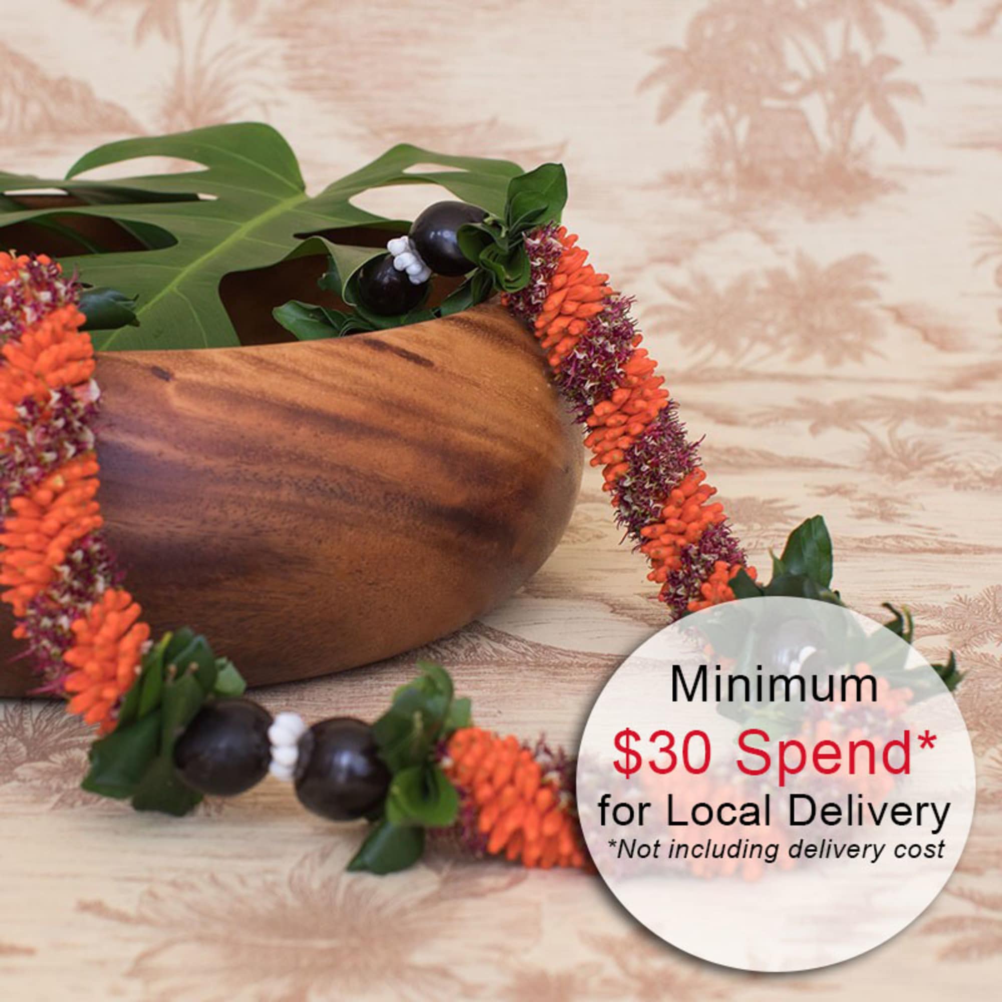 Tropical orange flower lei with dark beads draped beside a wooden bowl with a large leaf