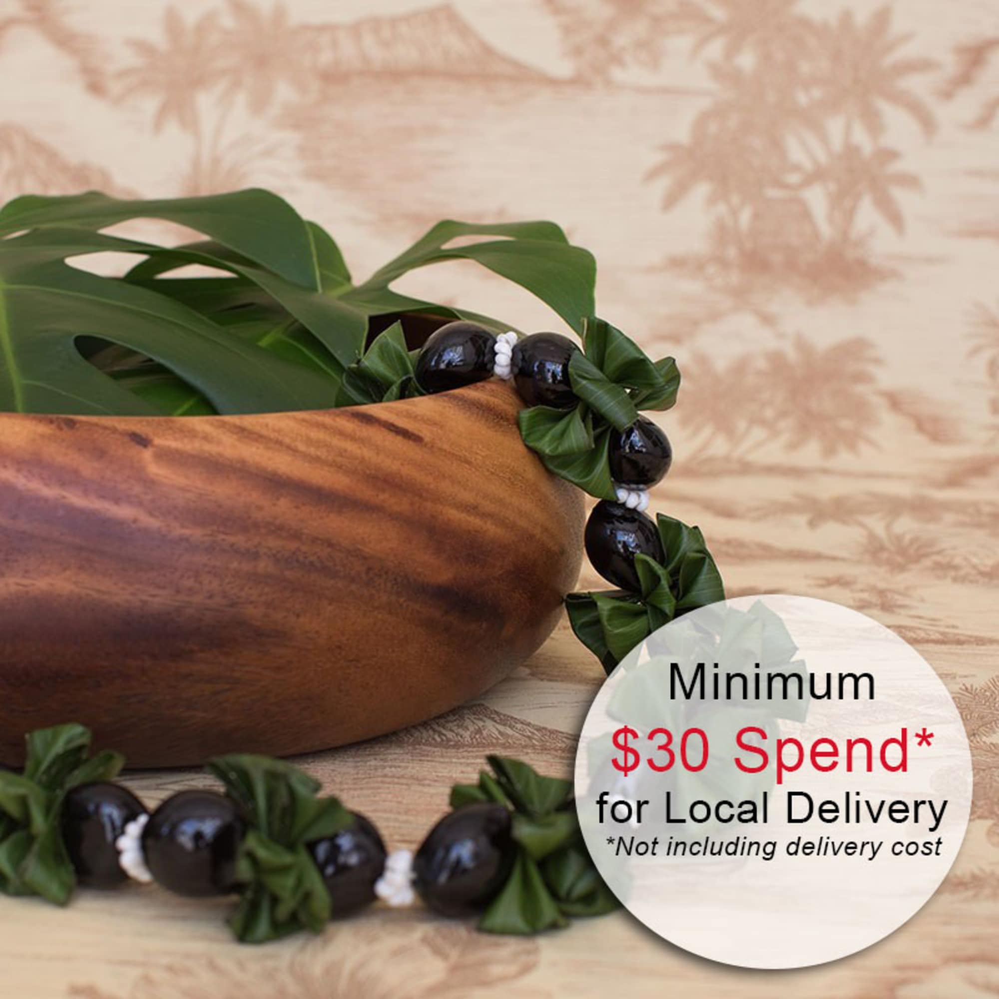 Wooden bowl with a tropical leaf and dark beaded lei on a patterned surface.