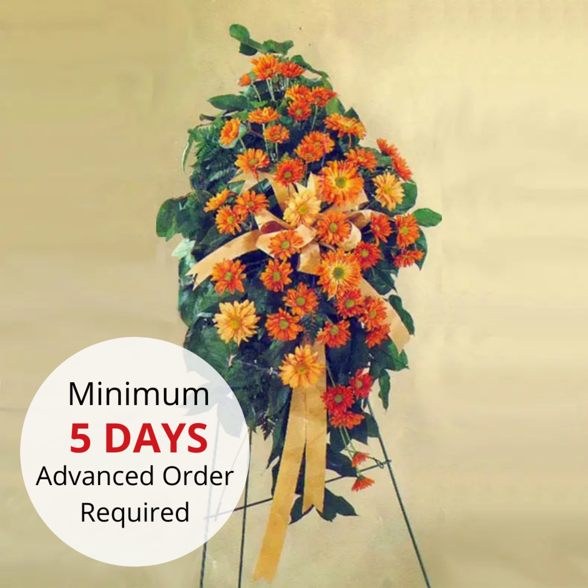 Tall standing spray of orange and yellow daisy flowers with matching ribbon on an easel stand