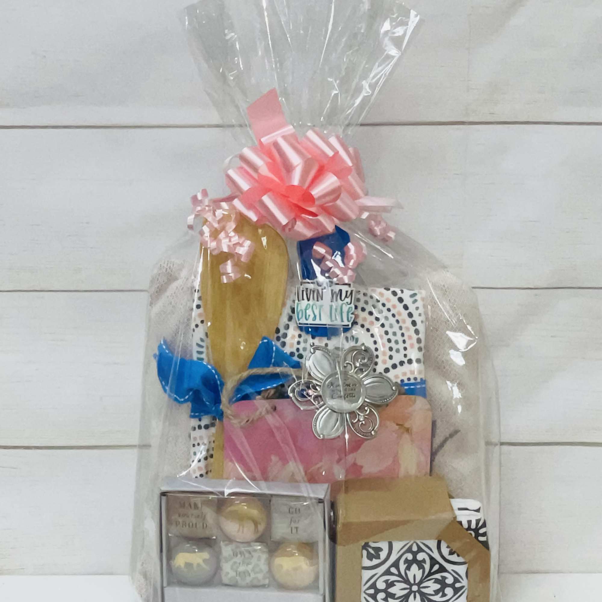 Cellophane-wrapped gift set with pink bow, assorted small boxes, and a silver flower charm
