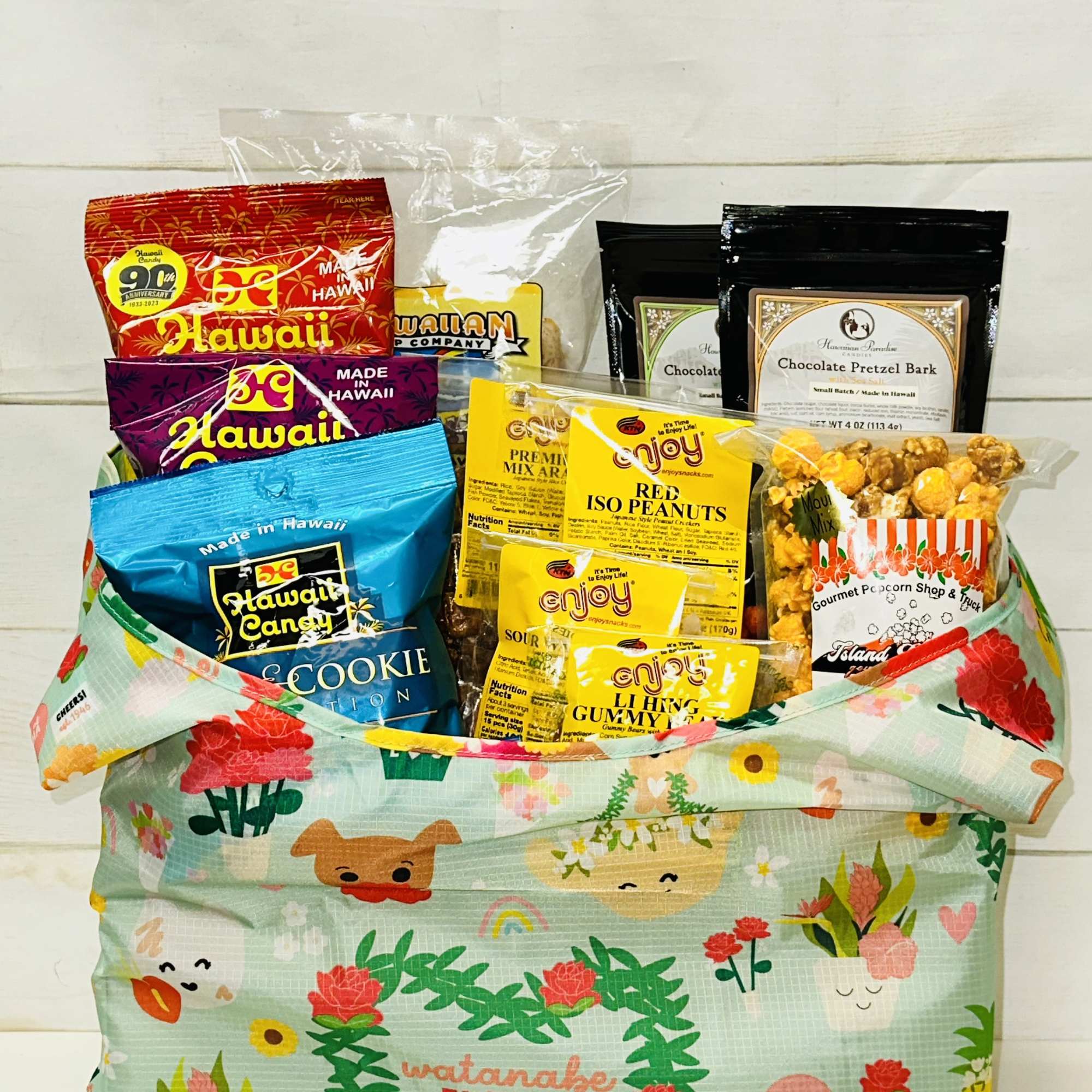 Colorful snack gift assortment in a patterned reusable tote bag with cartoon flowers and faces.