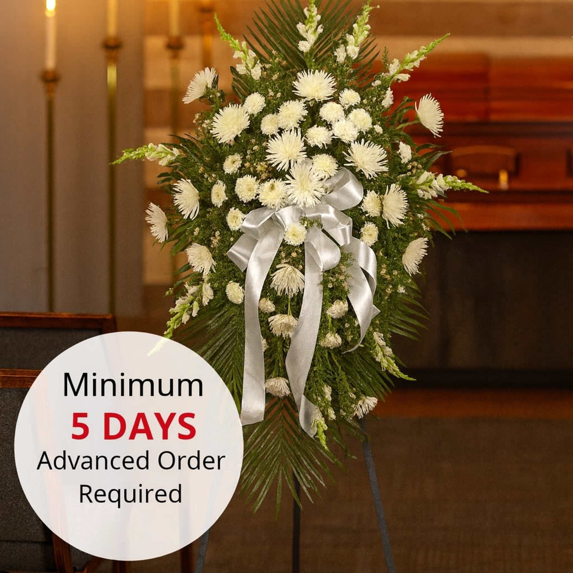 Tall white chrysanthemum standing spray with silver bow on an easel in a chapel setting