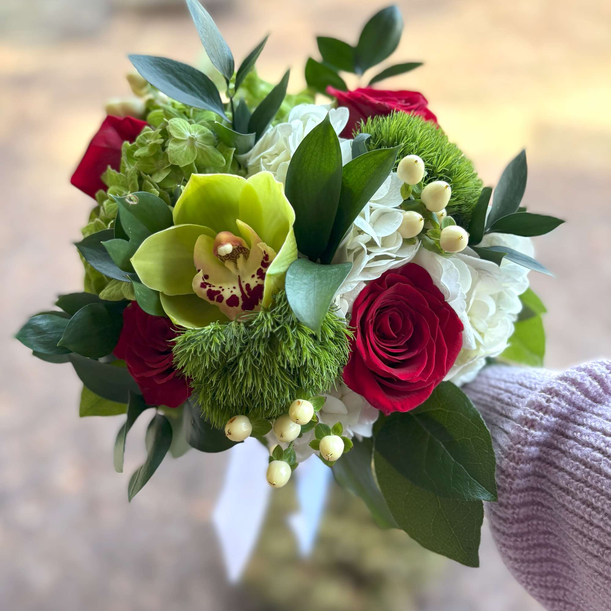 Hand-tied bouquet with red roses, green cymbidium orchid, white hydrangea, and green dianthus