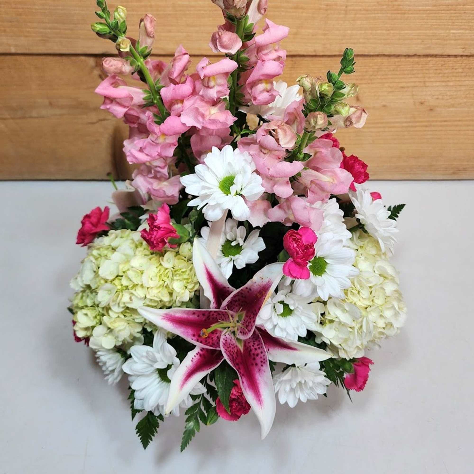 Pink snapdragons with white daisies, hydrangeas, and a pink lily arrangement