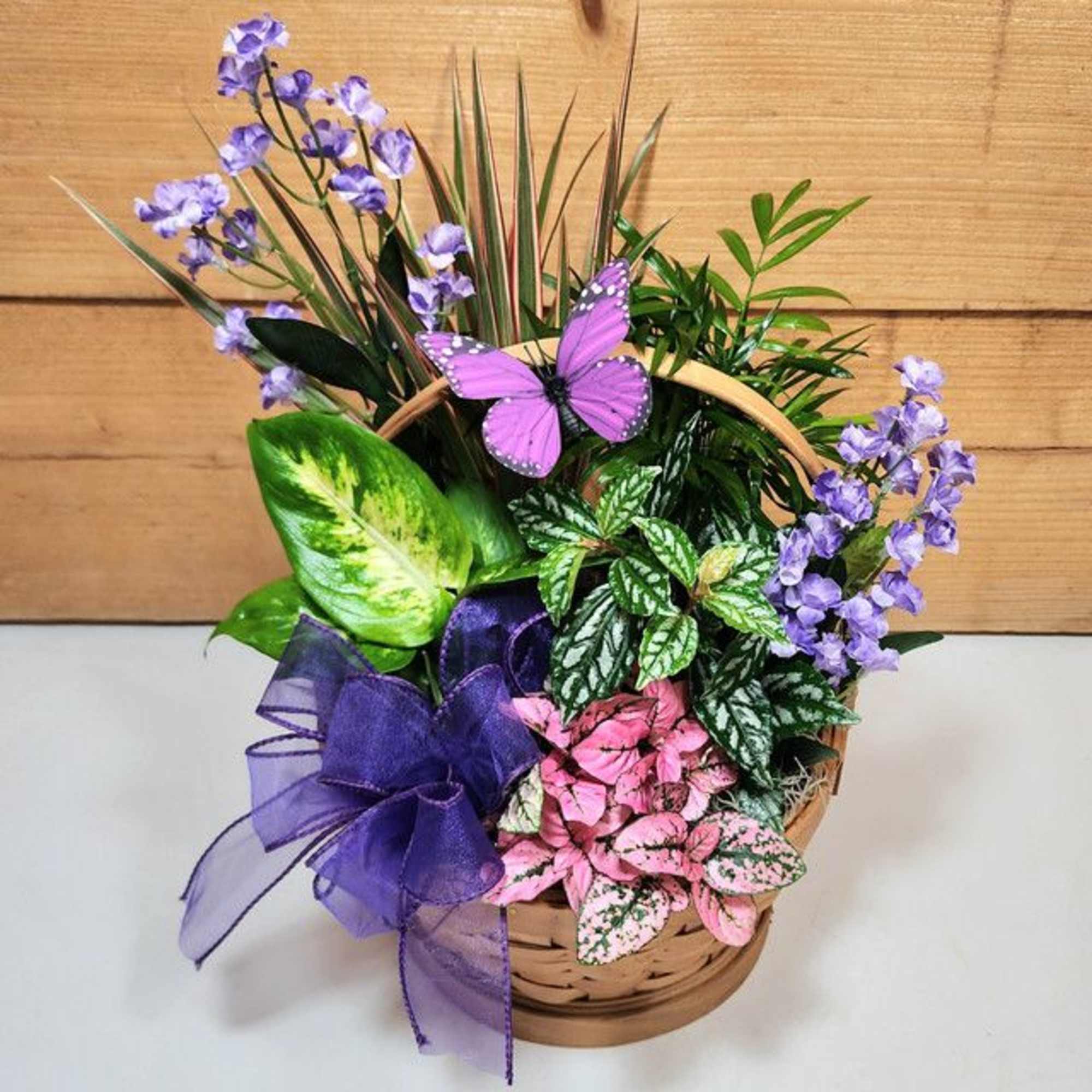 Basket of purple flowers and colorful foliage with a butterfly decoration