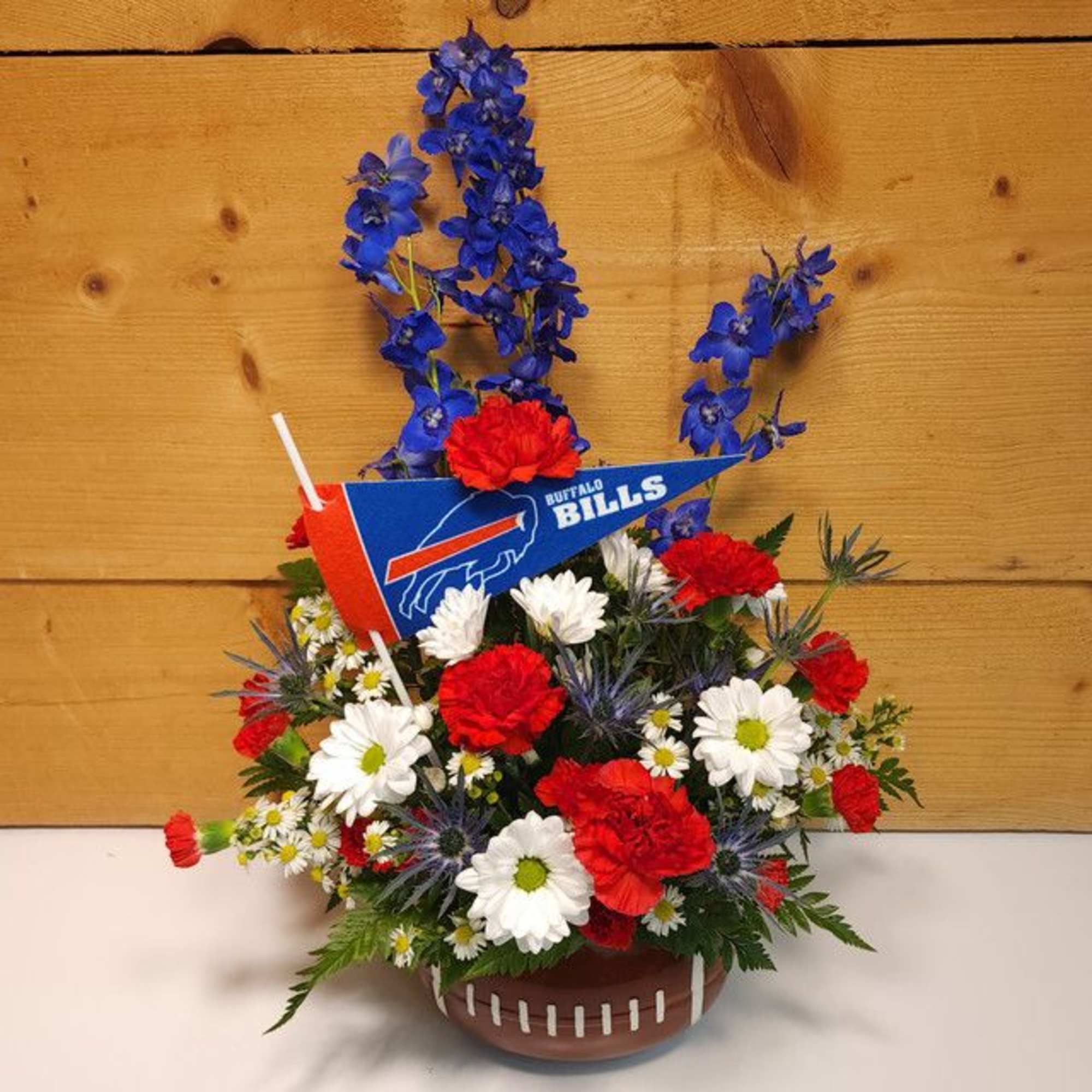 Football-themed flower arrangement in a football-shaped container with a Buffalo Bills pennant