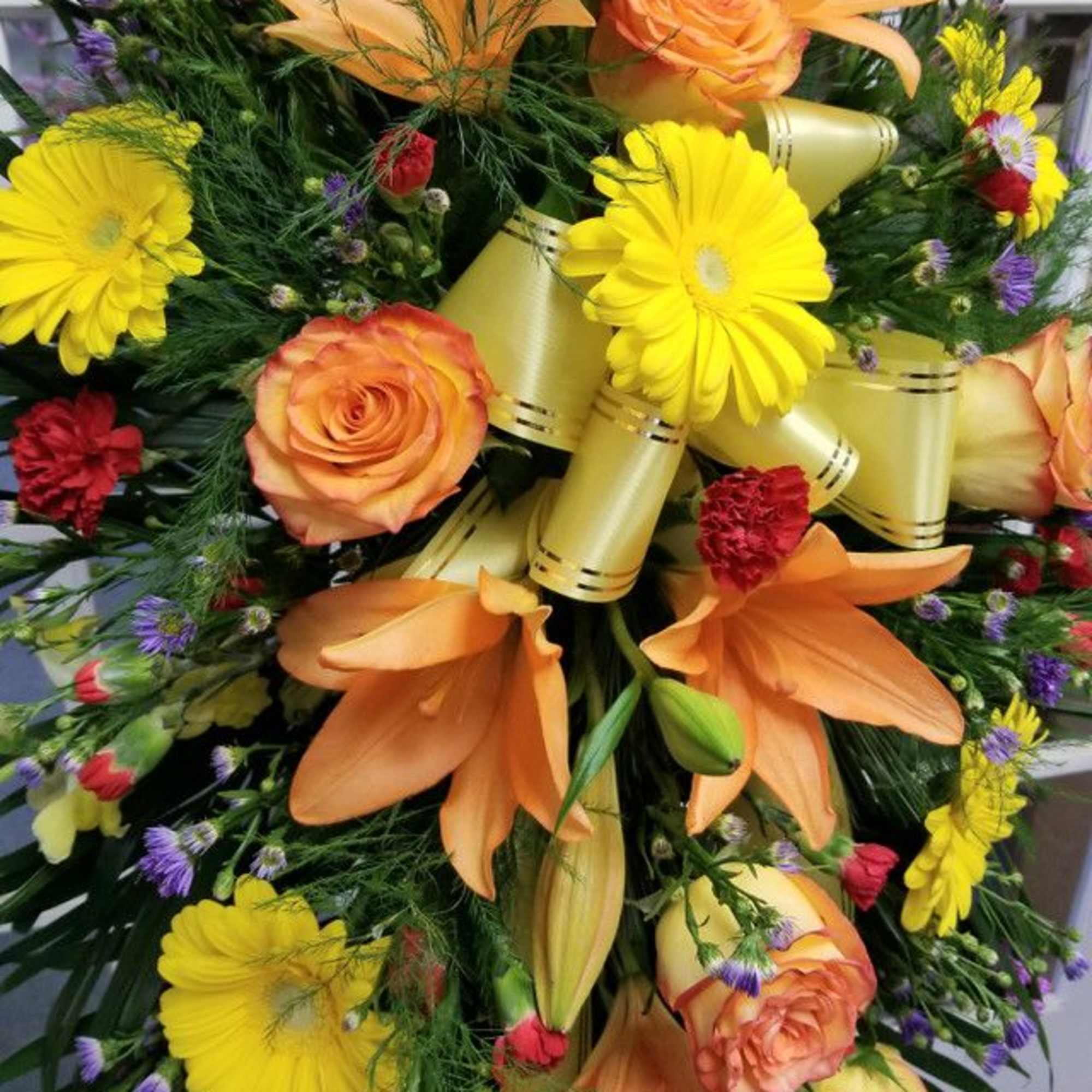 Orange lilies and roses with yellow daisies in a mixed bouquet