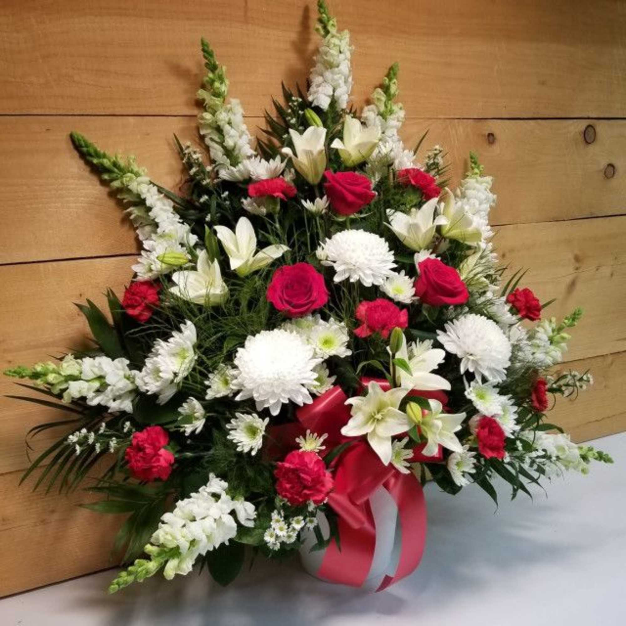 Large red, white, and pink funeral spray with lilies and roses