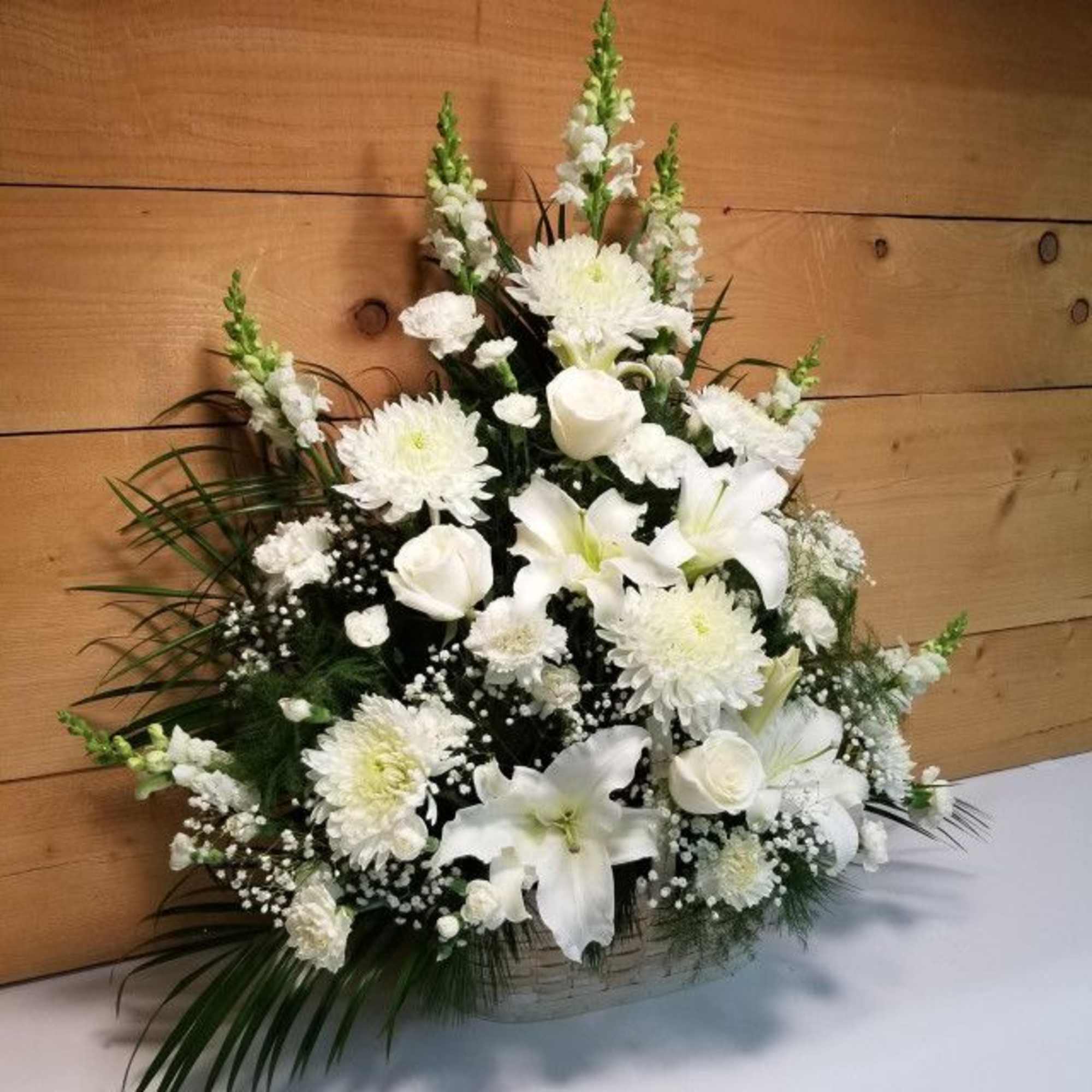 White floral arrangement in a basket with lilies and chrysanthemums