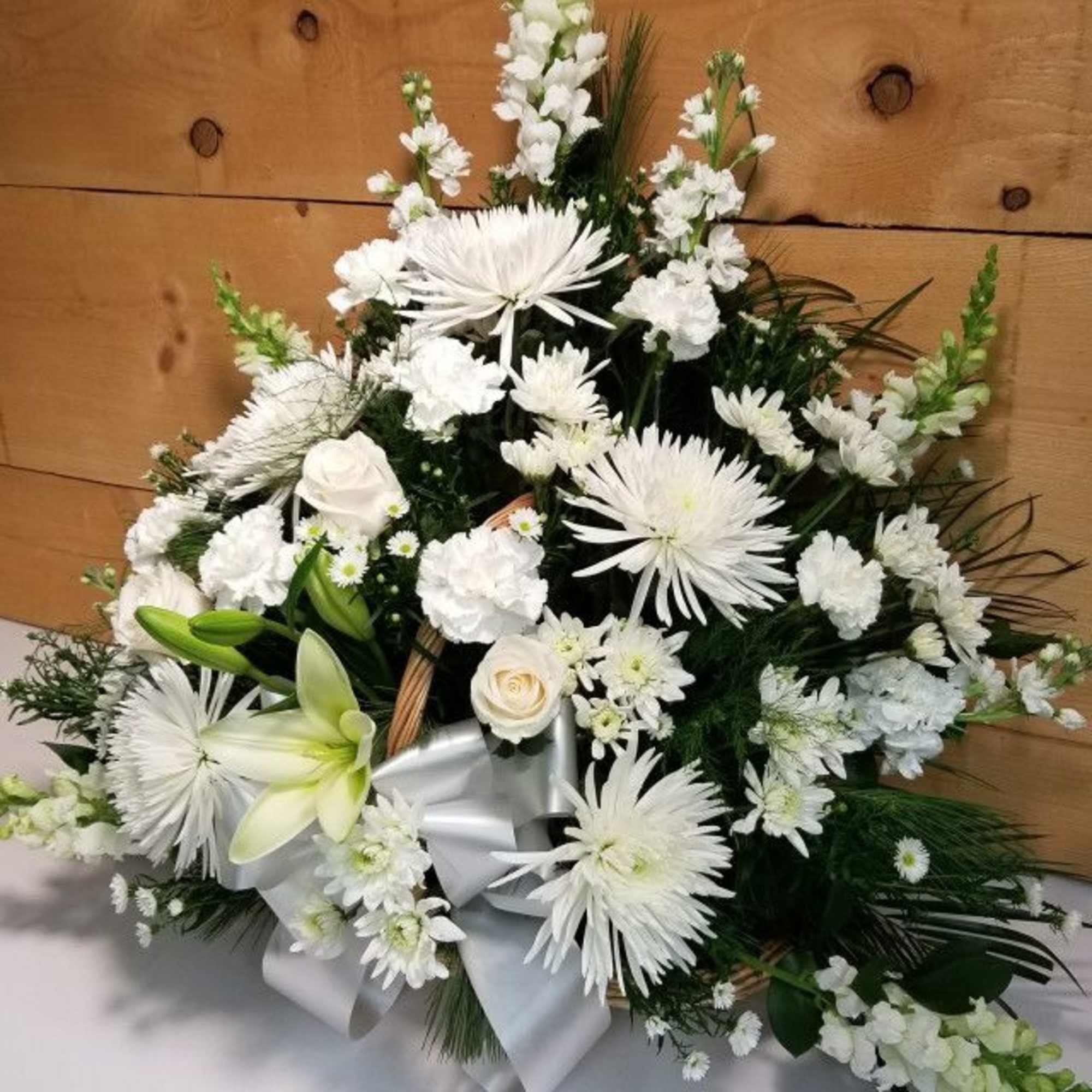 White floral arrangement with lilies, roses, and daisies in a basket