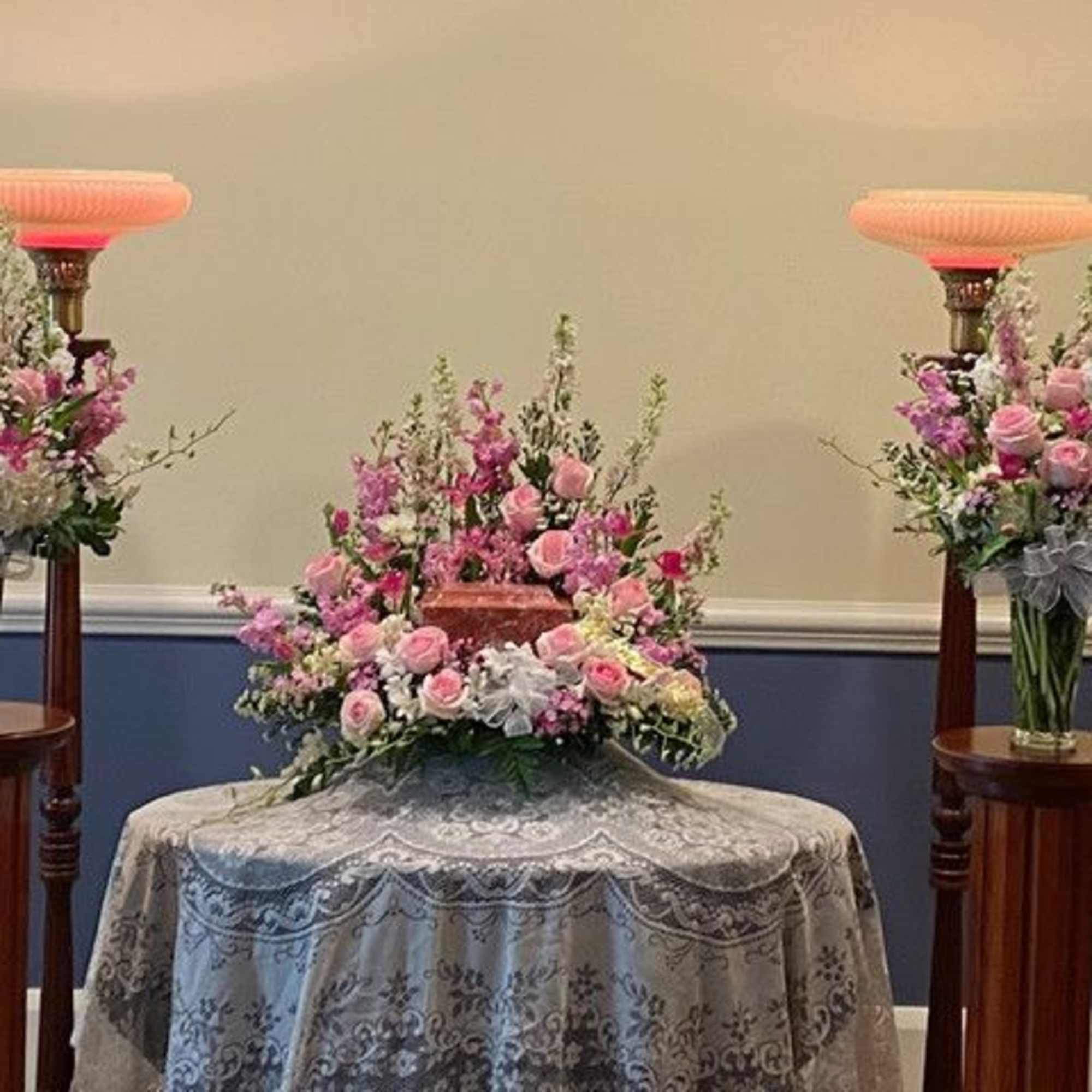 Pink floral arrangements on pedestals around a table centerpiece