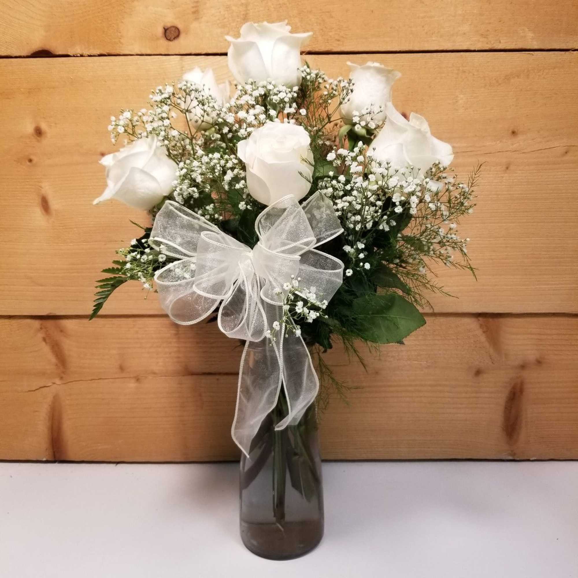 White roses in a glass vase with a sheer ribbon bow