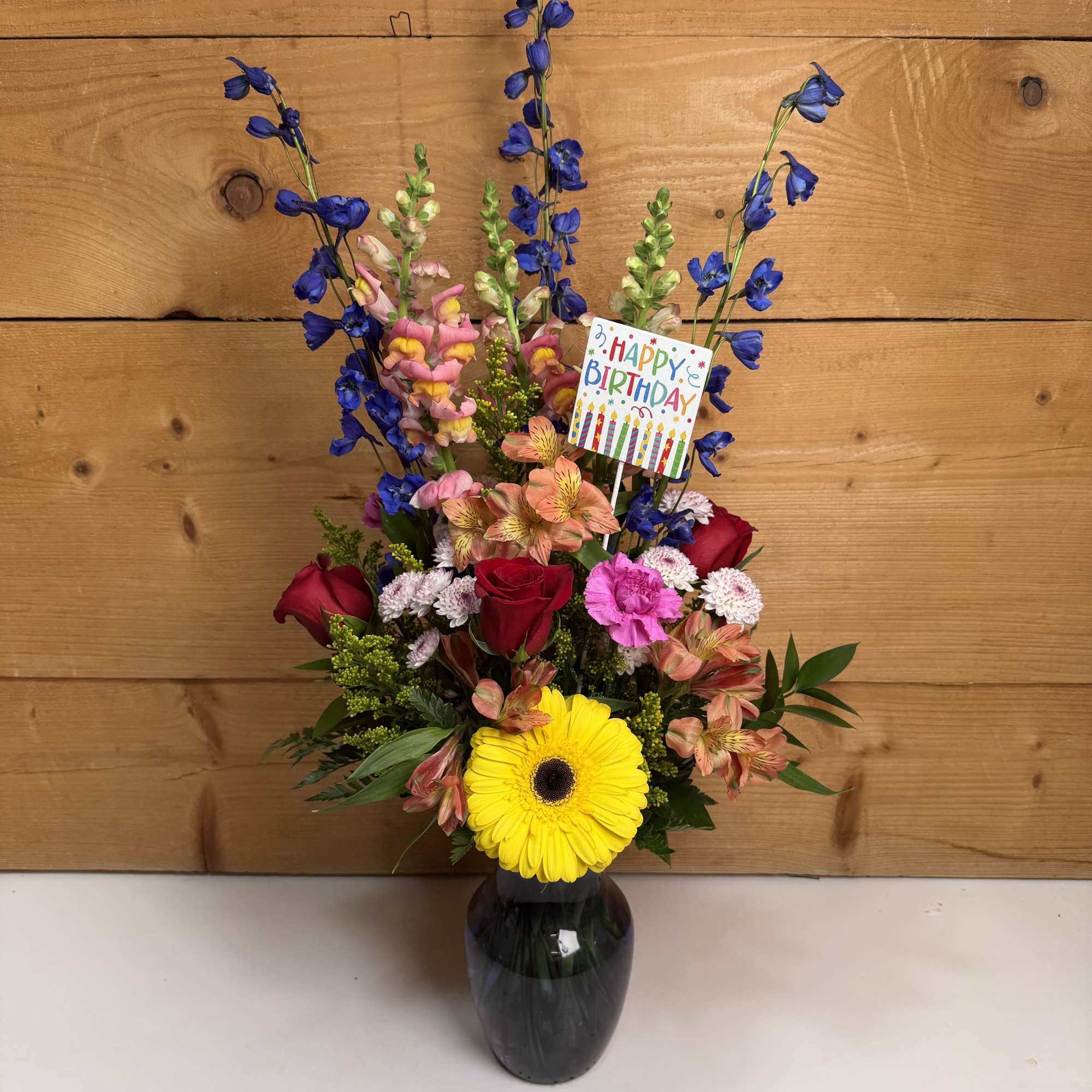 Colorful birthday bouquet in a dark vase with a card