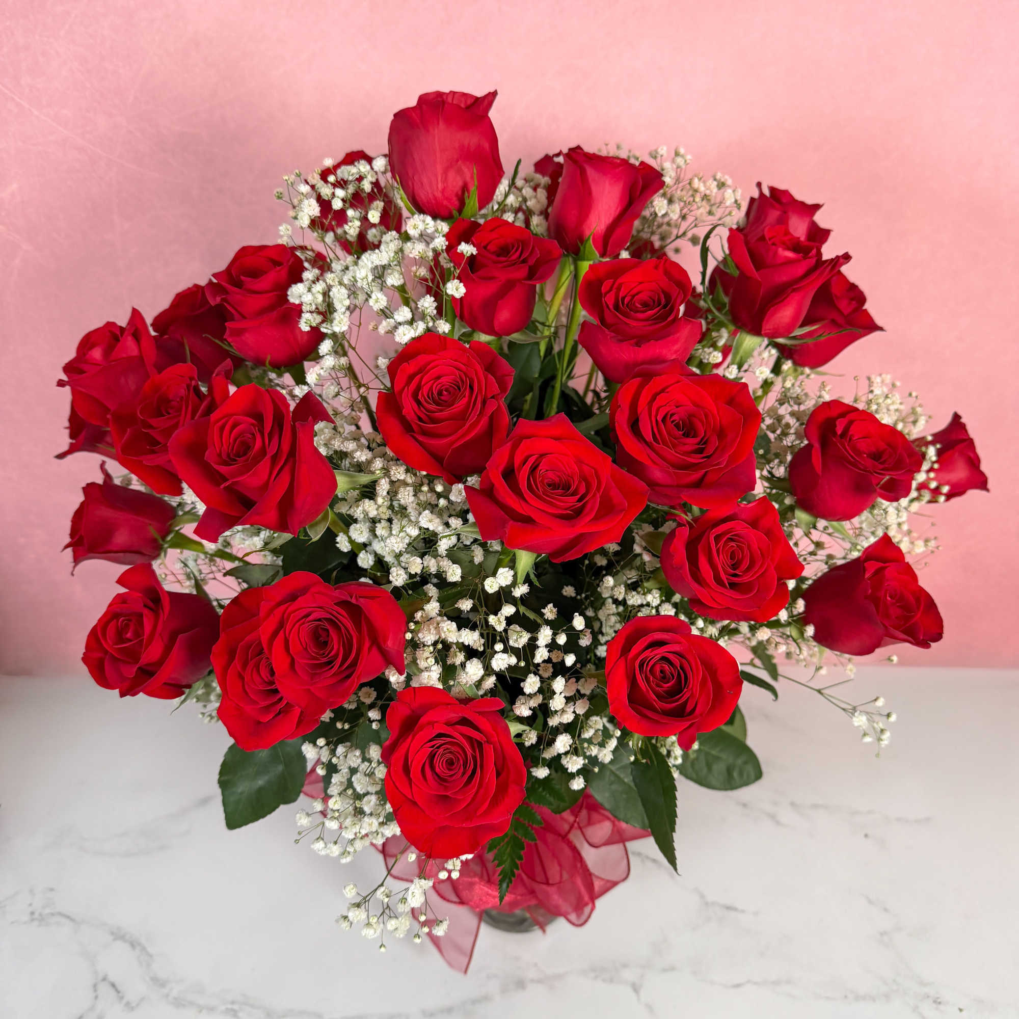 Bouquet of red roses with white baby's breath in a clear vase