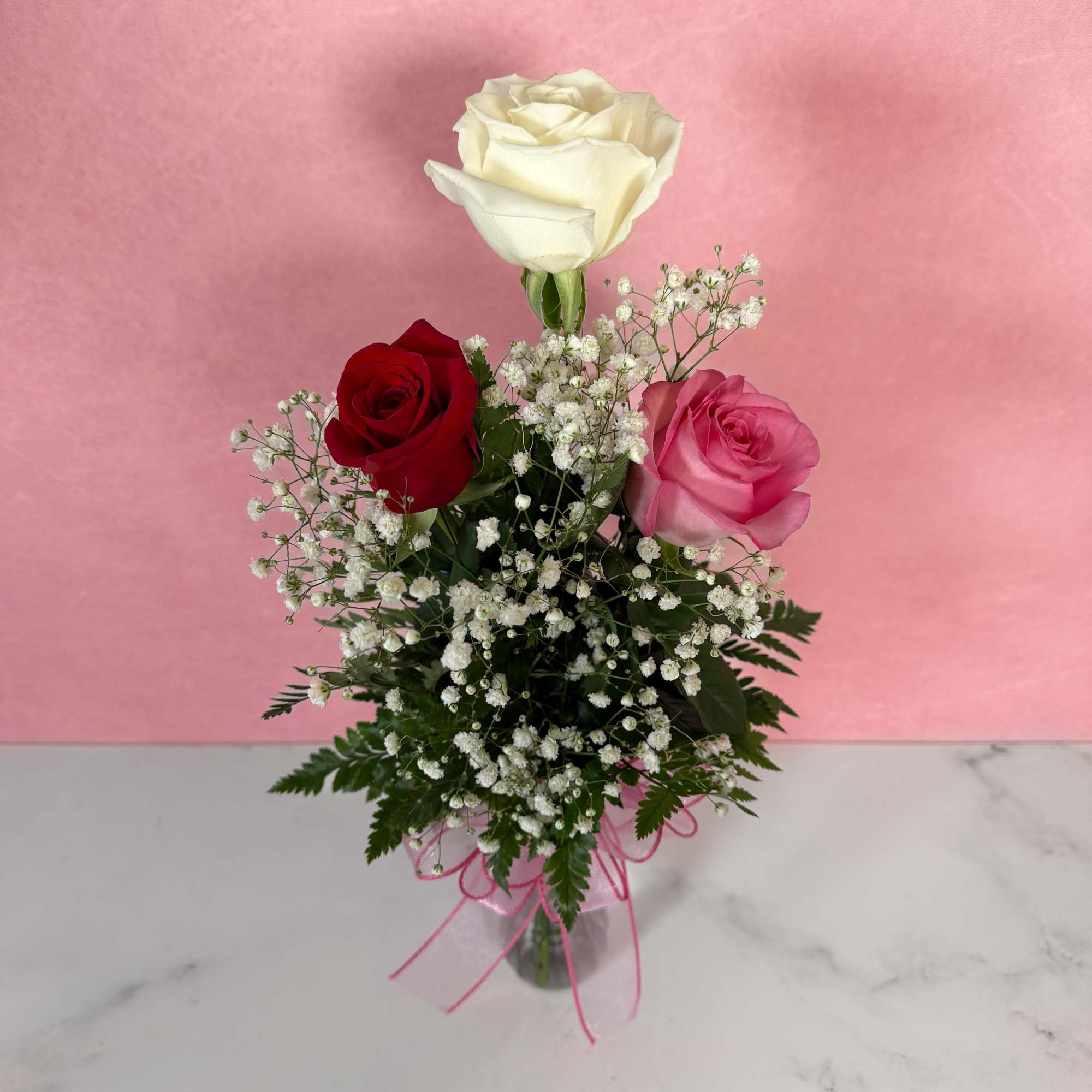 Three roses with baby's breath in a small vase