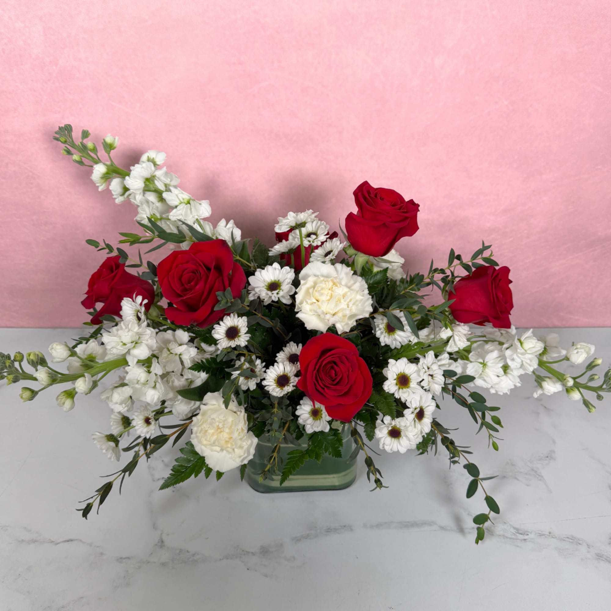 Red roses and white flowers in a low glass vase