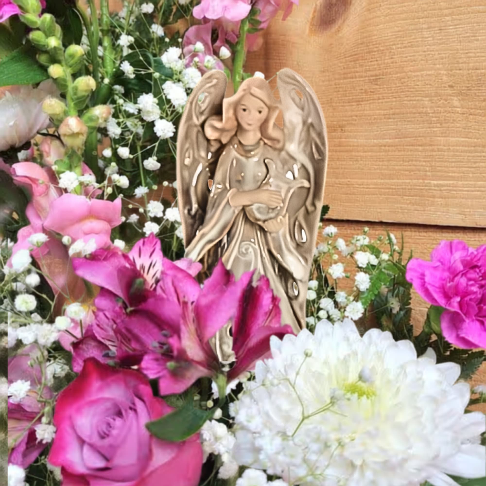 Pink and white flowers arranged around a small angel figurine
