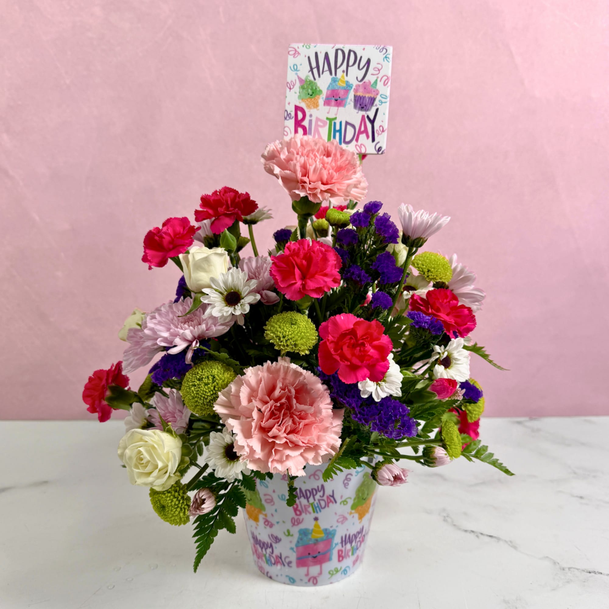 Mixed pink, white, purple, and green flowers in a birthday cup