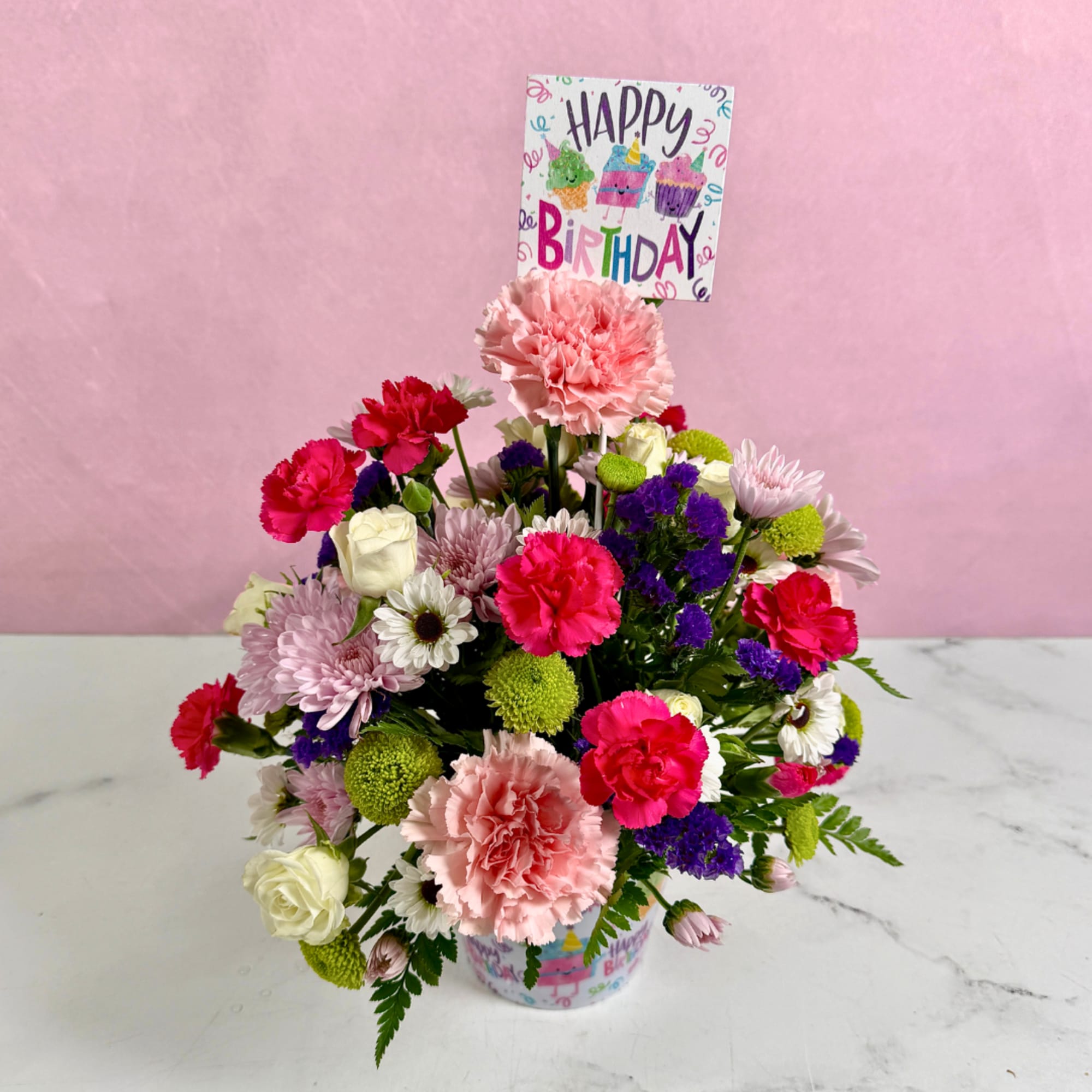 Mixed flower arrangement in a birthday container with a Happy Birthday card